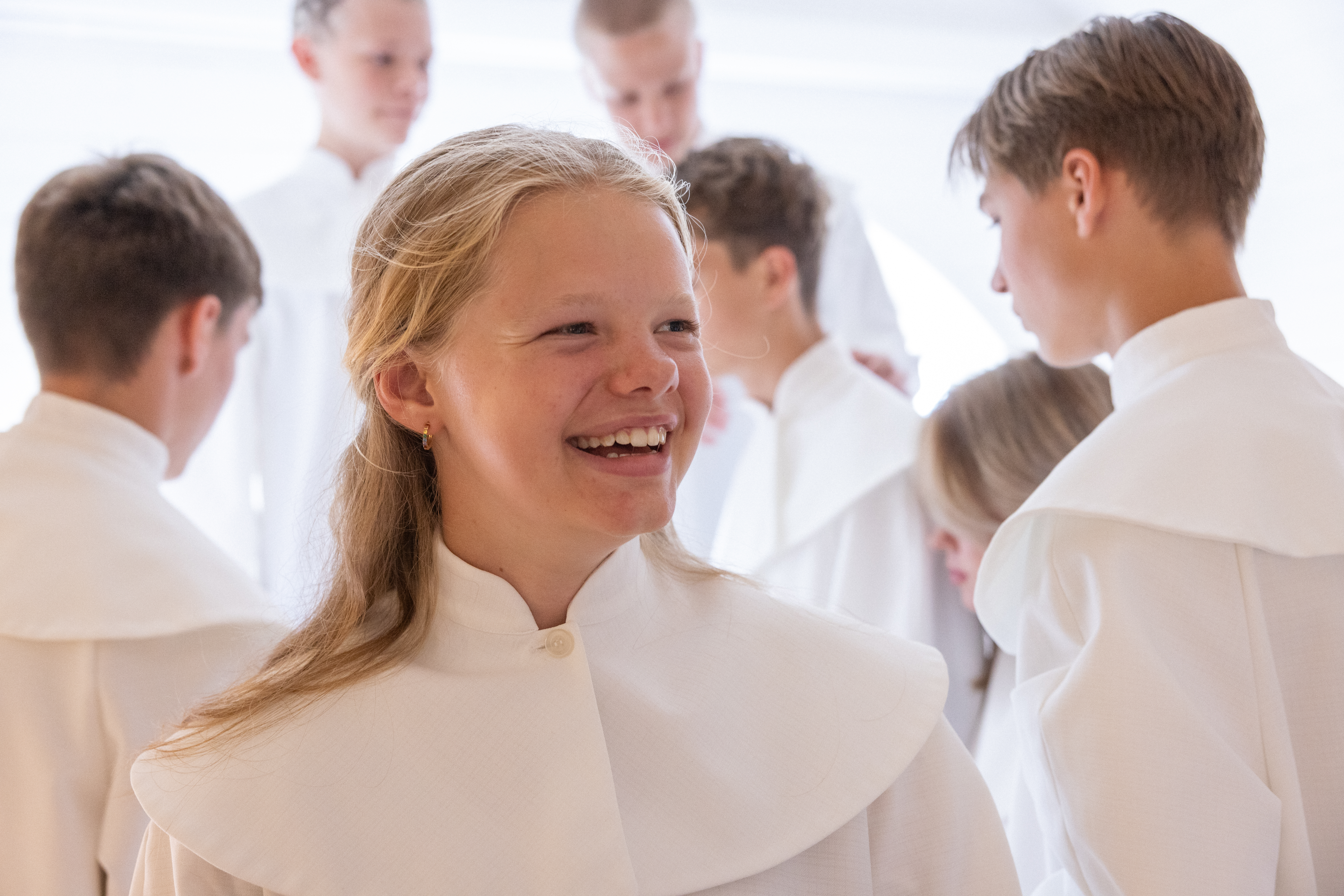 En glad konfirmand i förgrunden och flera konfirmander i bakgrunden