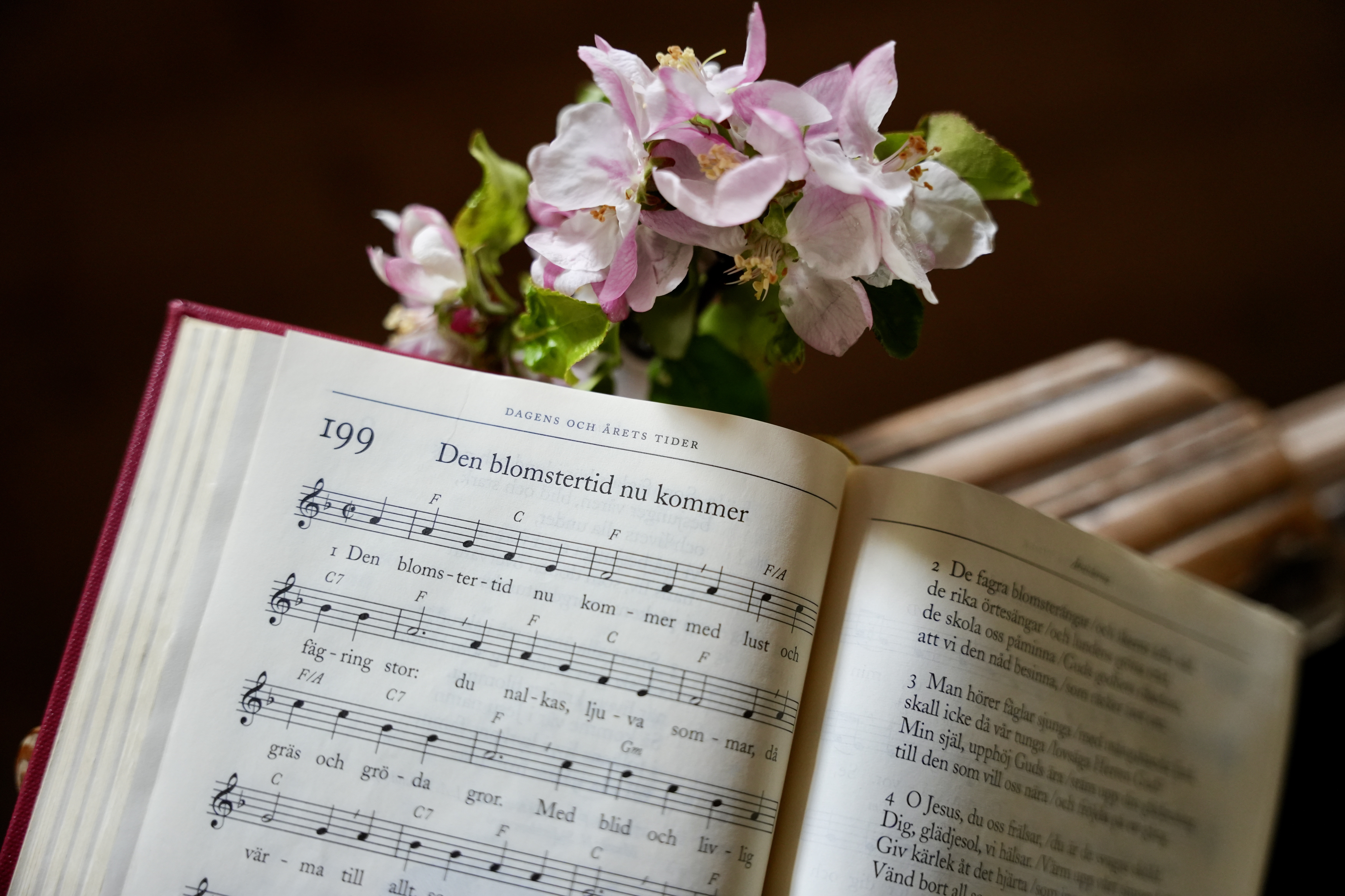 Uppslagen psalmbok med text och musik till psalmen "Den blomstertid nu kommer"
