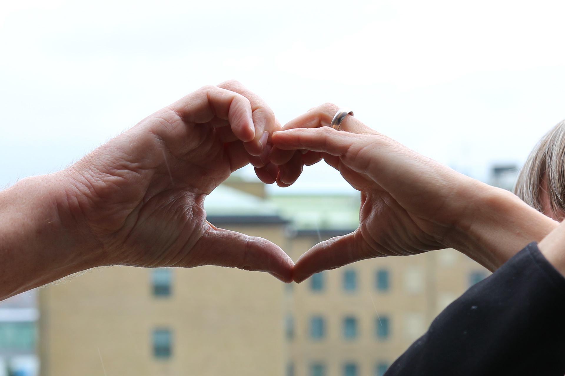 Två händer möts och formar tillsammans ett hjärta.