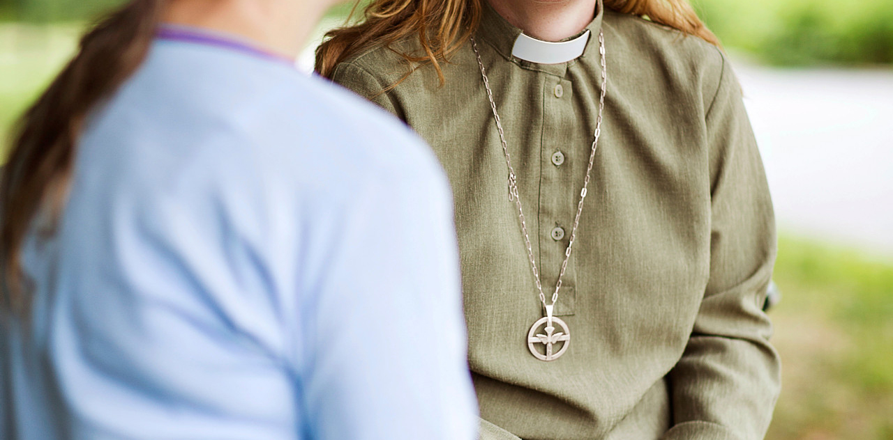 En diakon samtalar med en person utomhus.