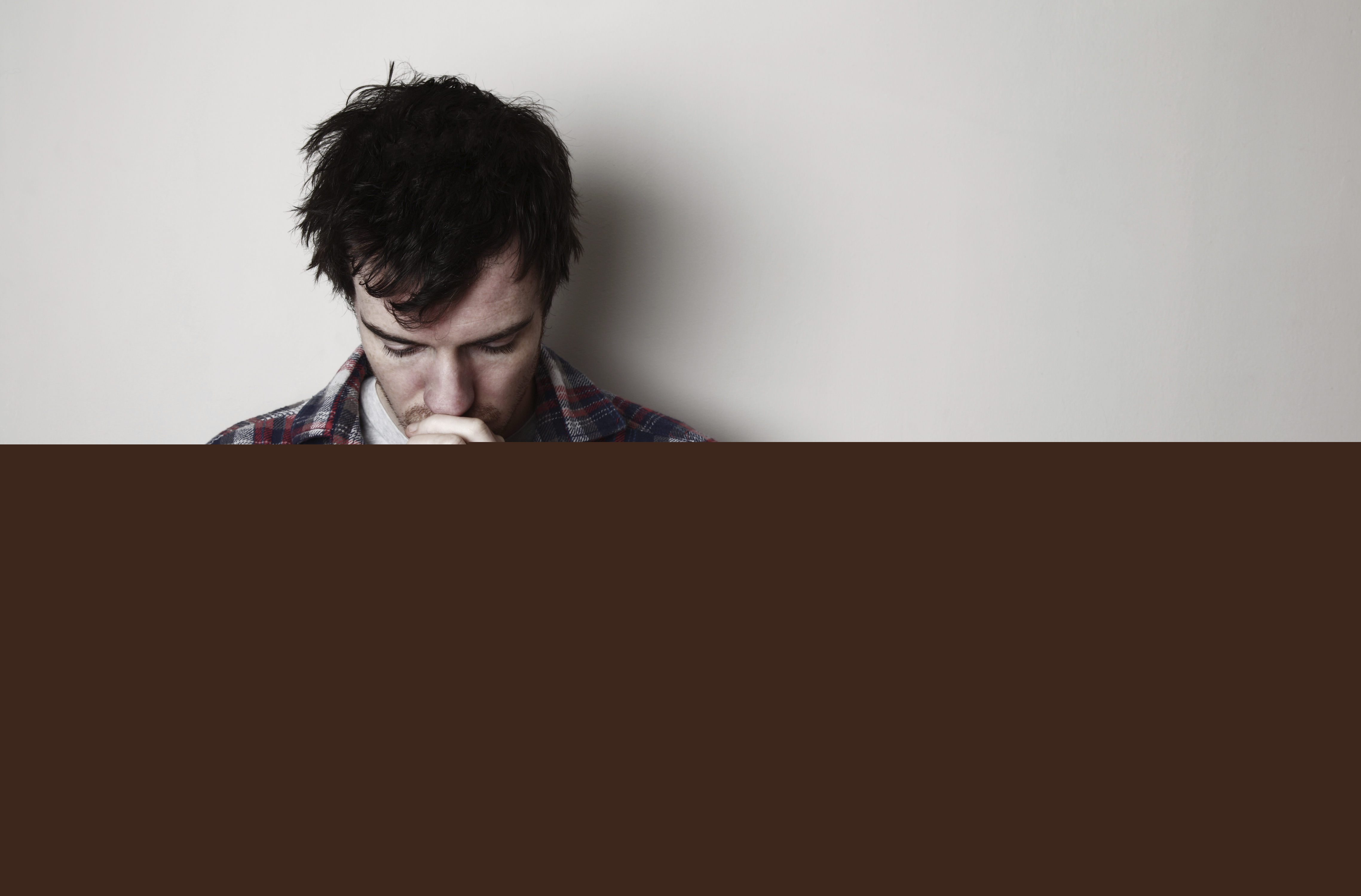 Vuxen ung man med rutig skjorta som ber.