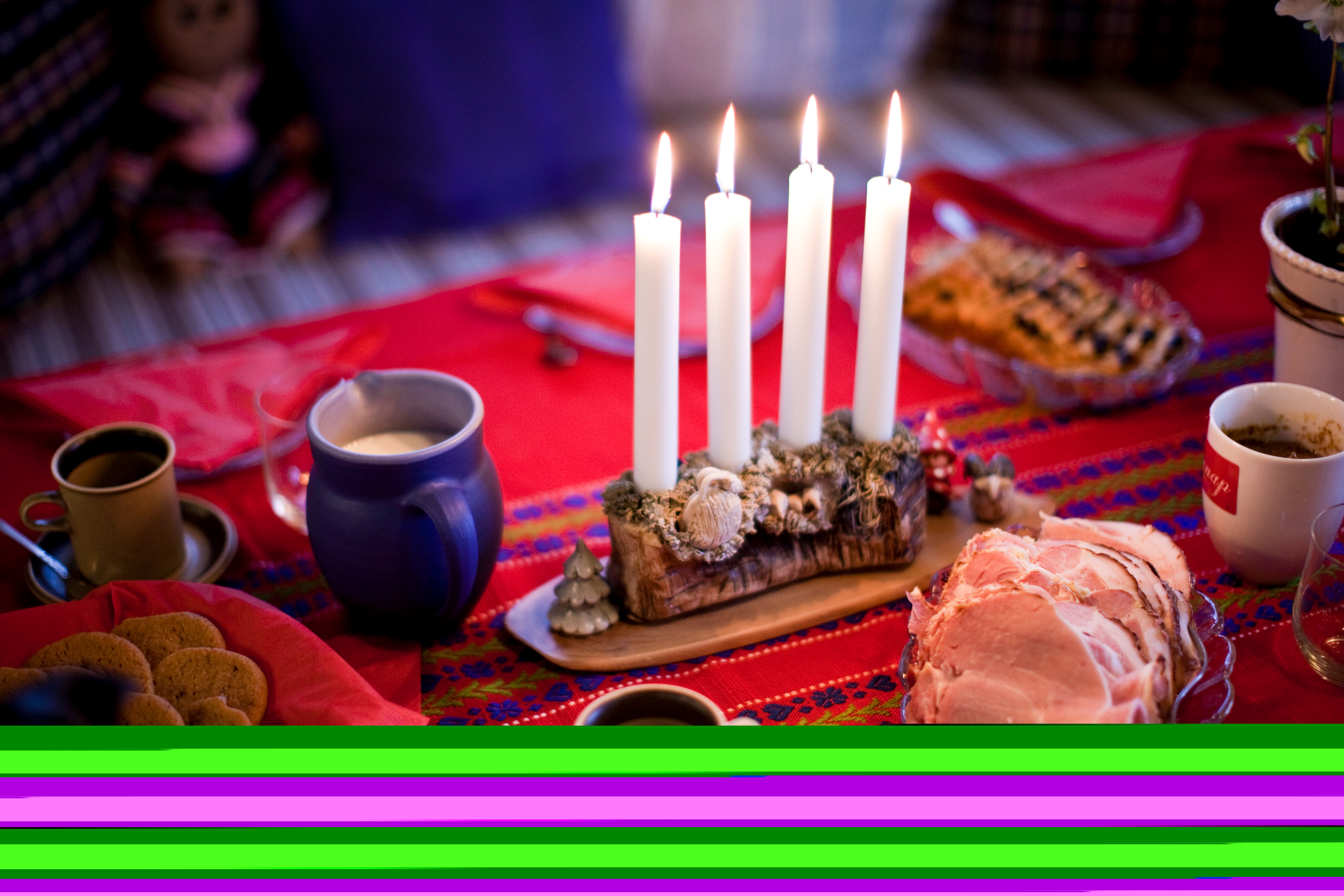 En adventsljusstake med alla ljus tända står på ett julbord.