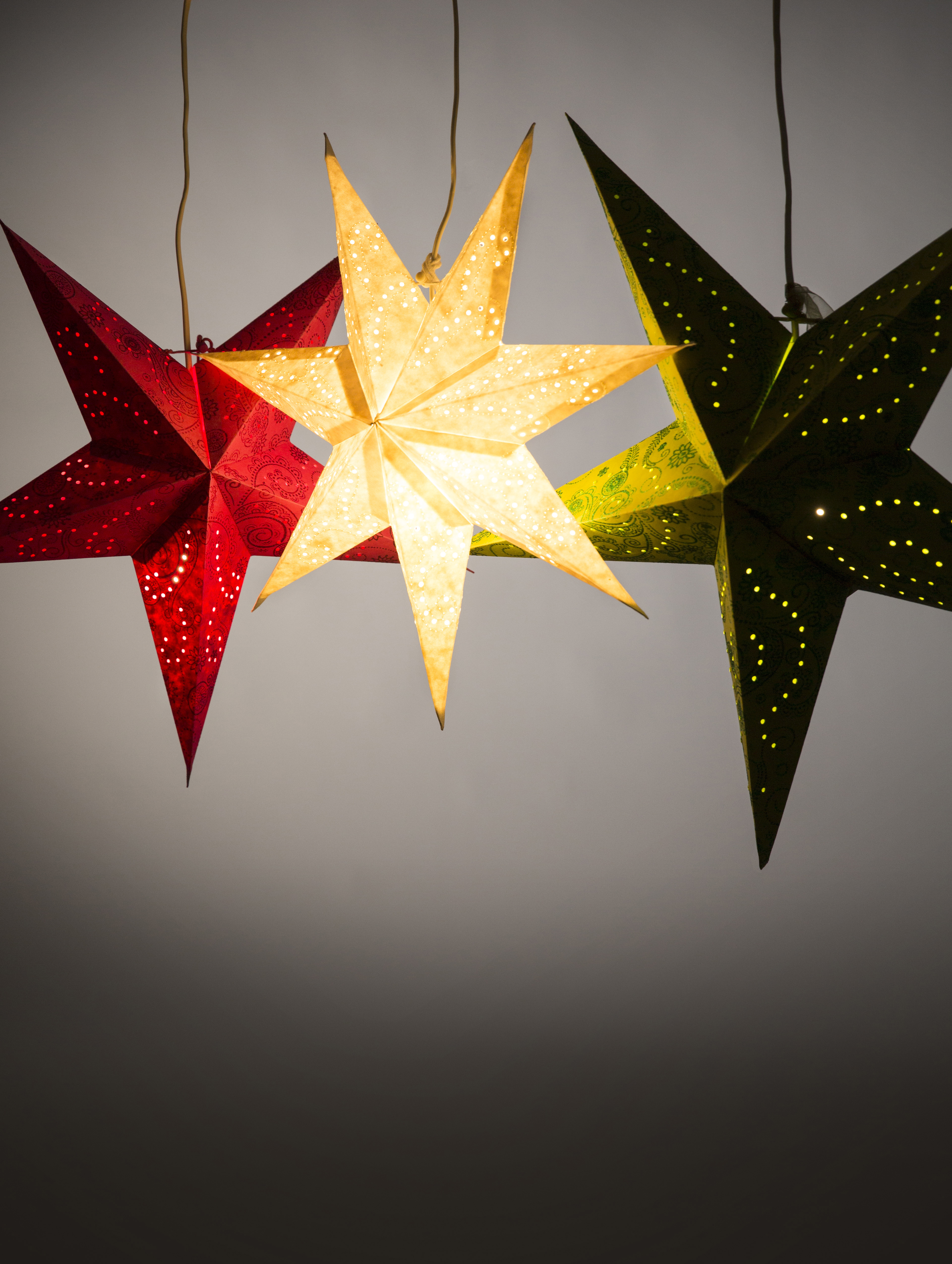 En röd, en vit och en grön adventsstjärna hänger i taket.
