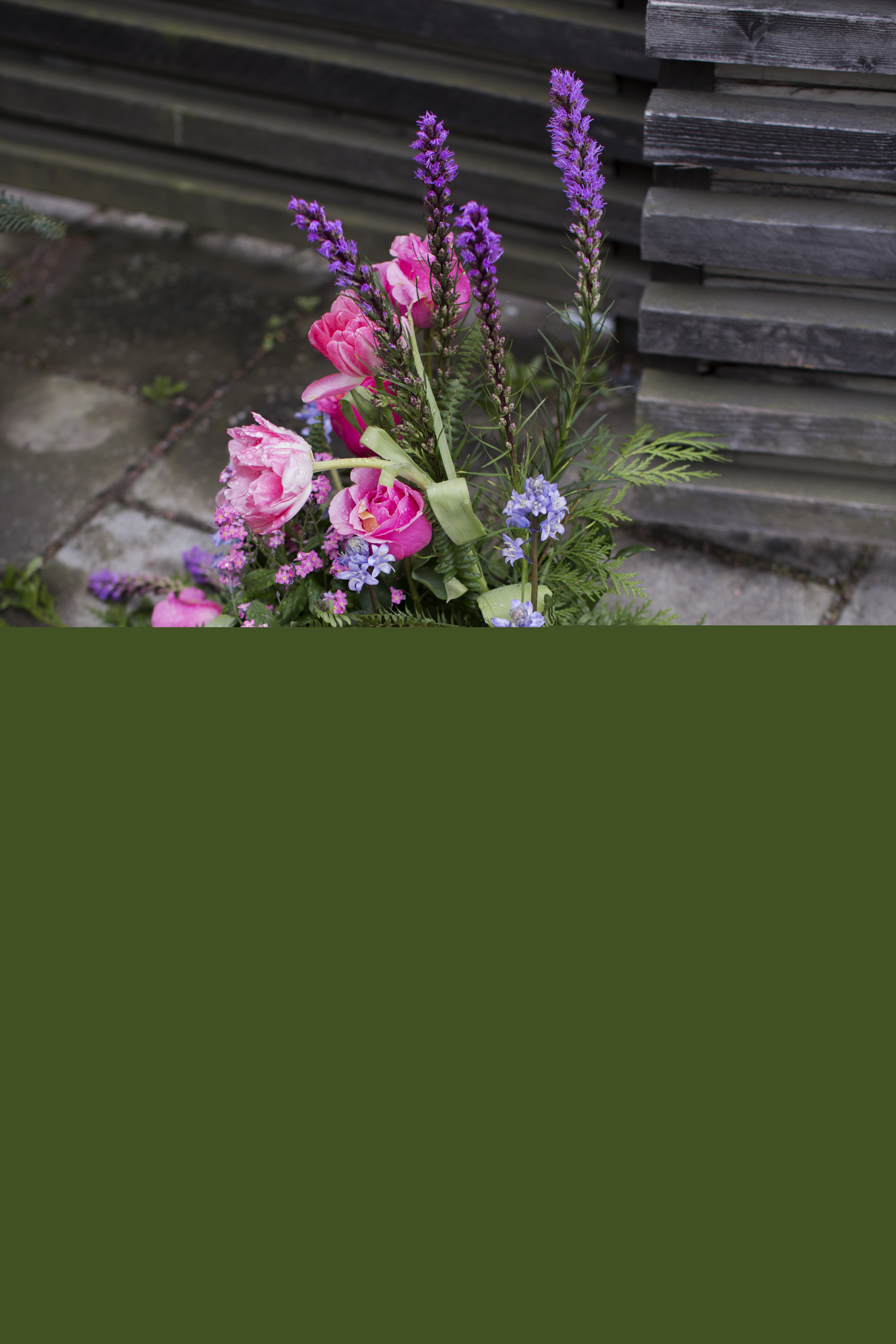 En stor begravningsbukett ligger utomhus på marken.