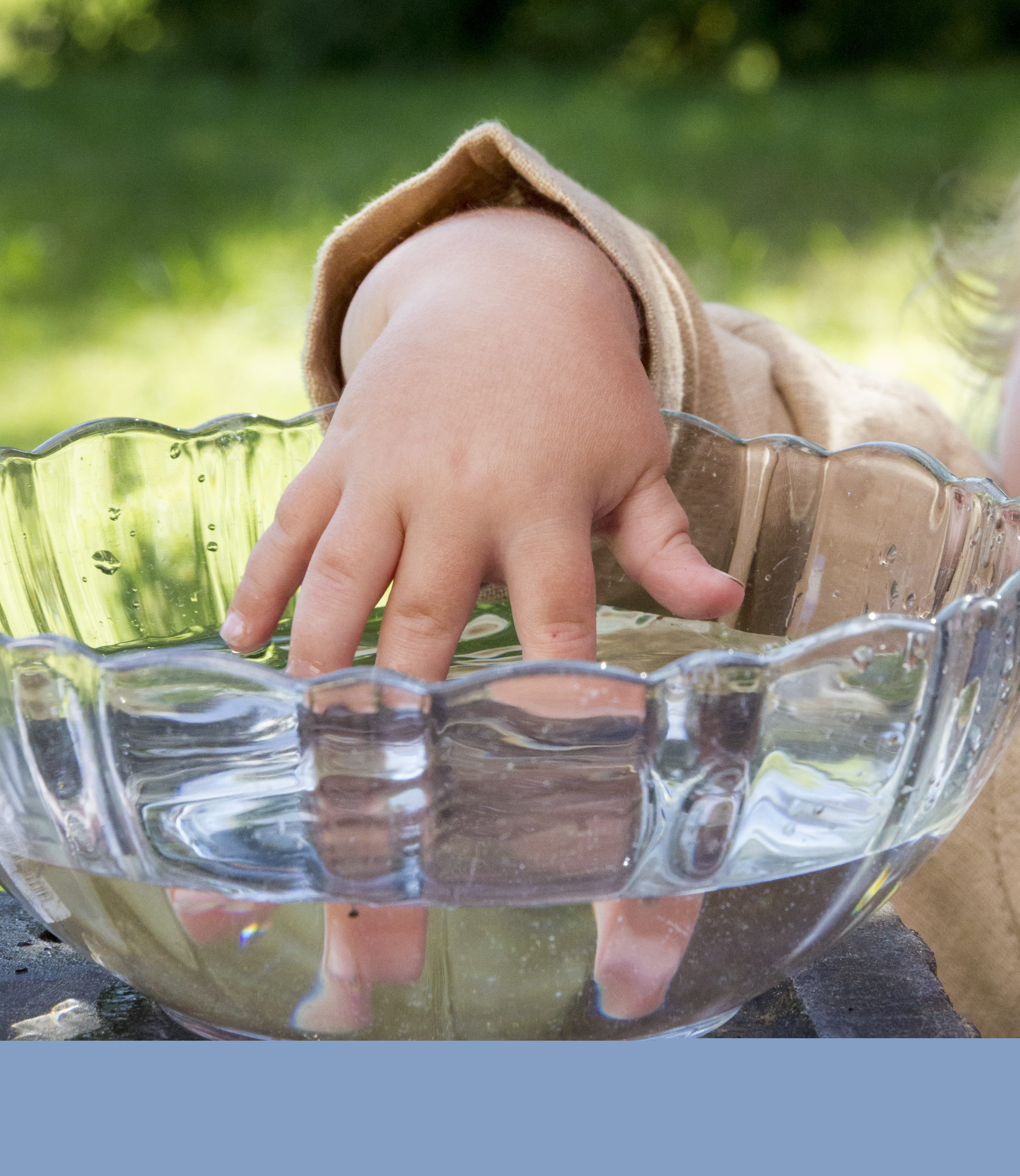 En bebis doppar handen i en skål med vatten.