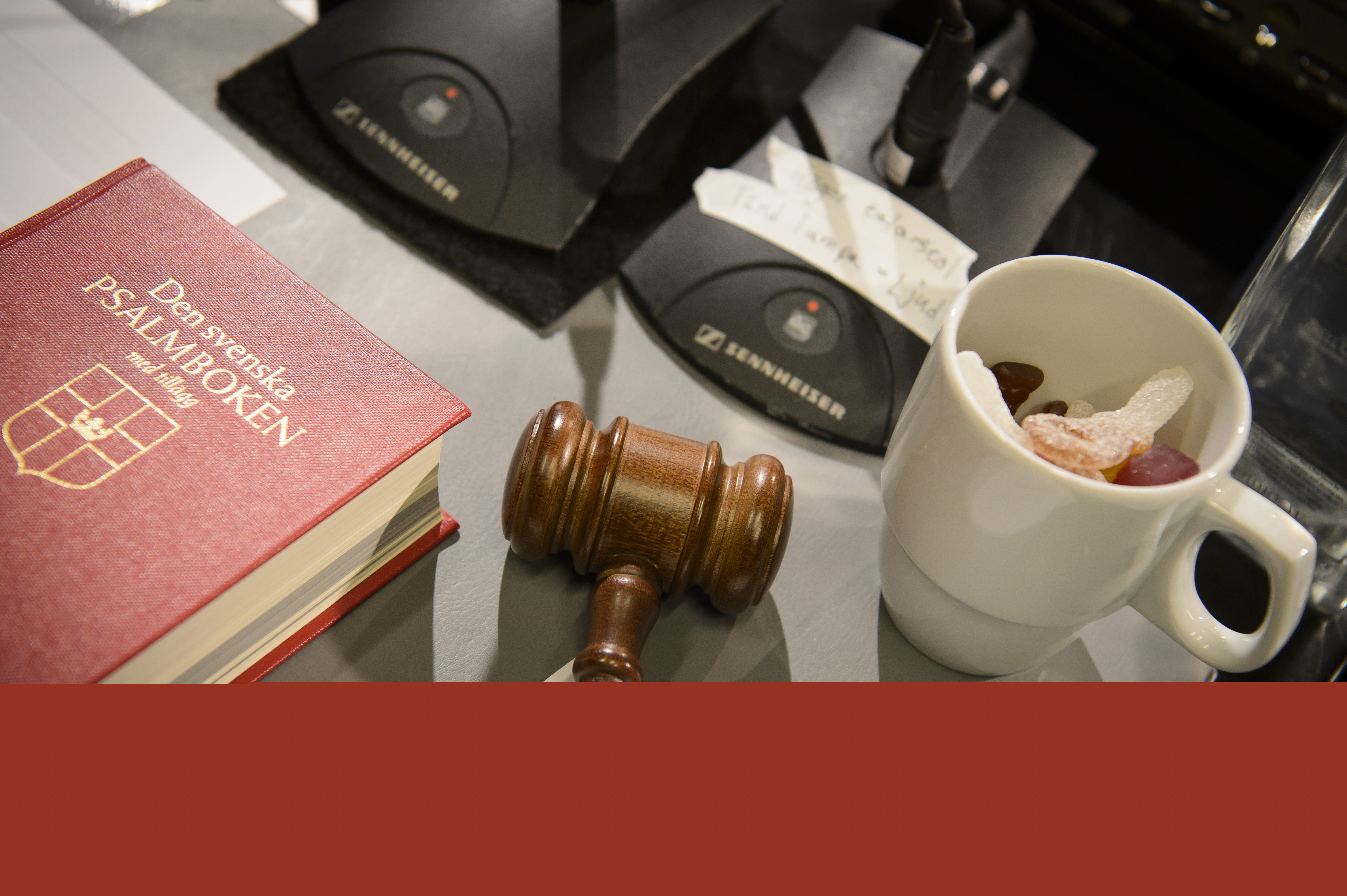 En psalmbok, en kopp med godis och en träklubba ligger på ett bord.