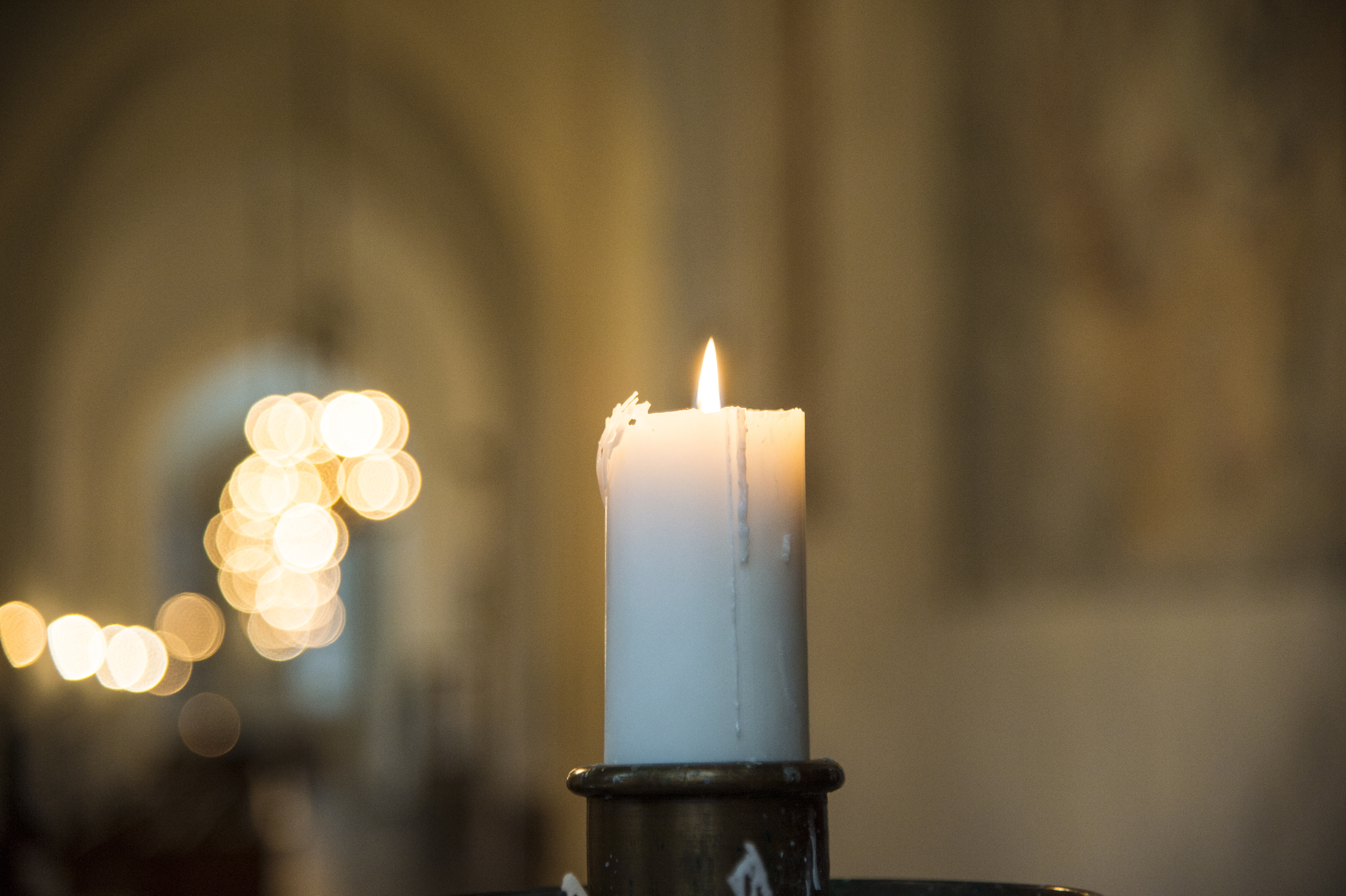 Ett tänt stearinljus i en kyrka.