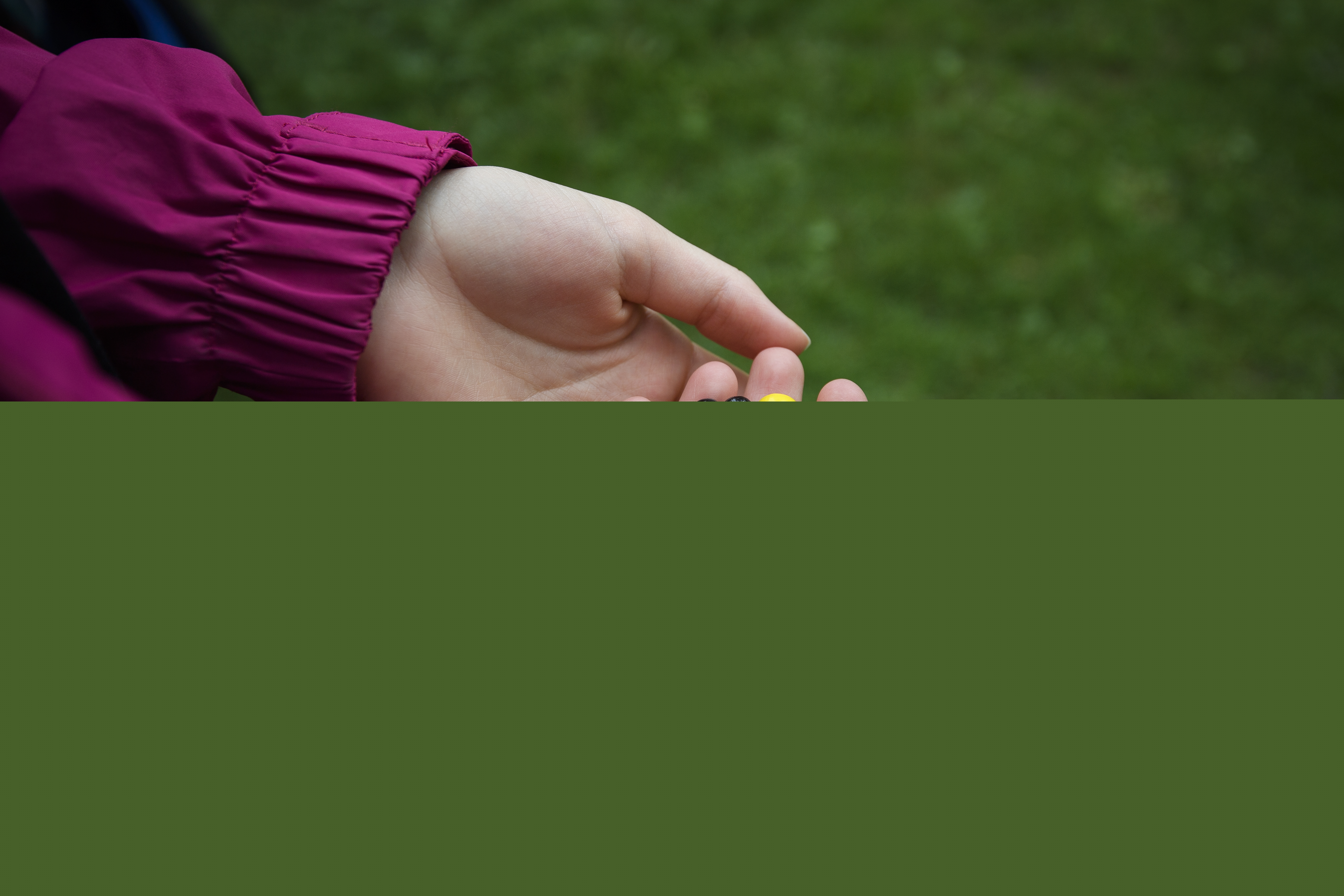 En person håller i ett pärlarmband med pärlor i olika färger och former.