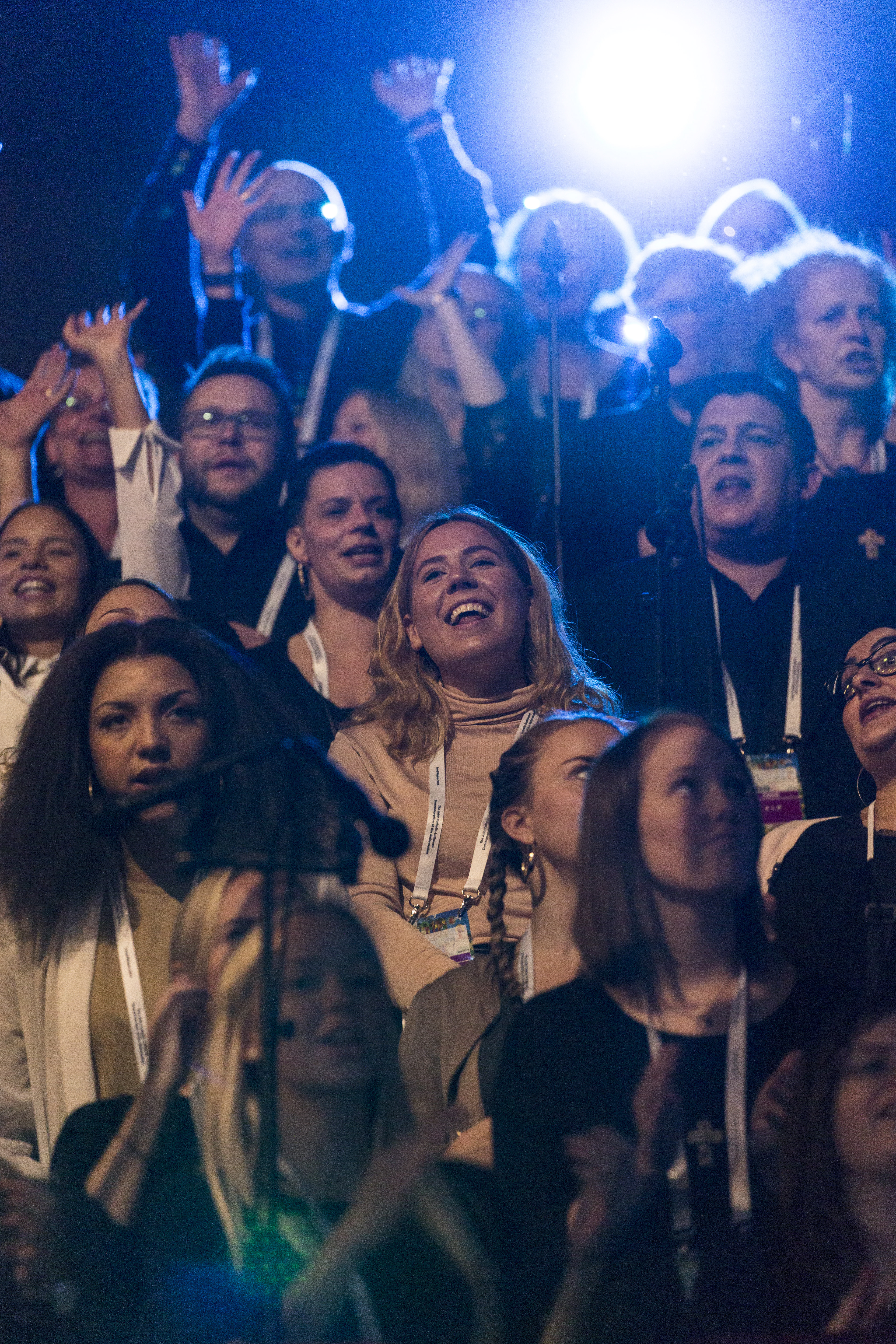 Närbild på en kör med glada sångare. Några sträcker armarna mot skyn.