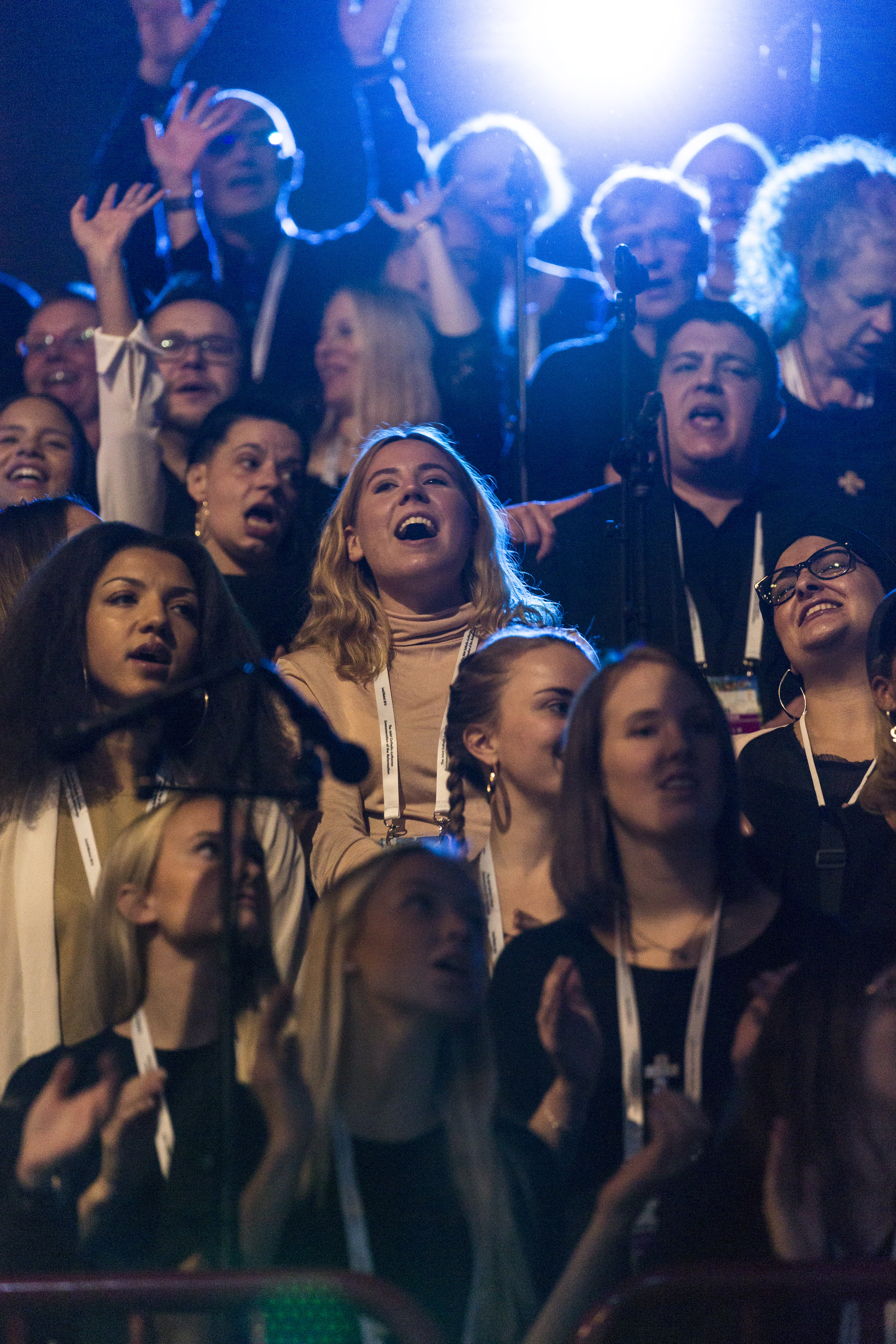 Närbild på en ungdomskör som sjunger. Några har armarna i luften.
