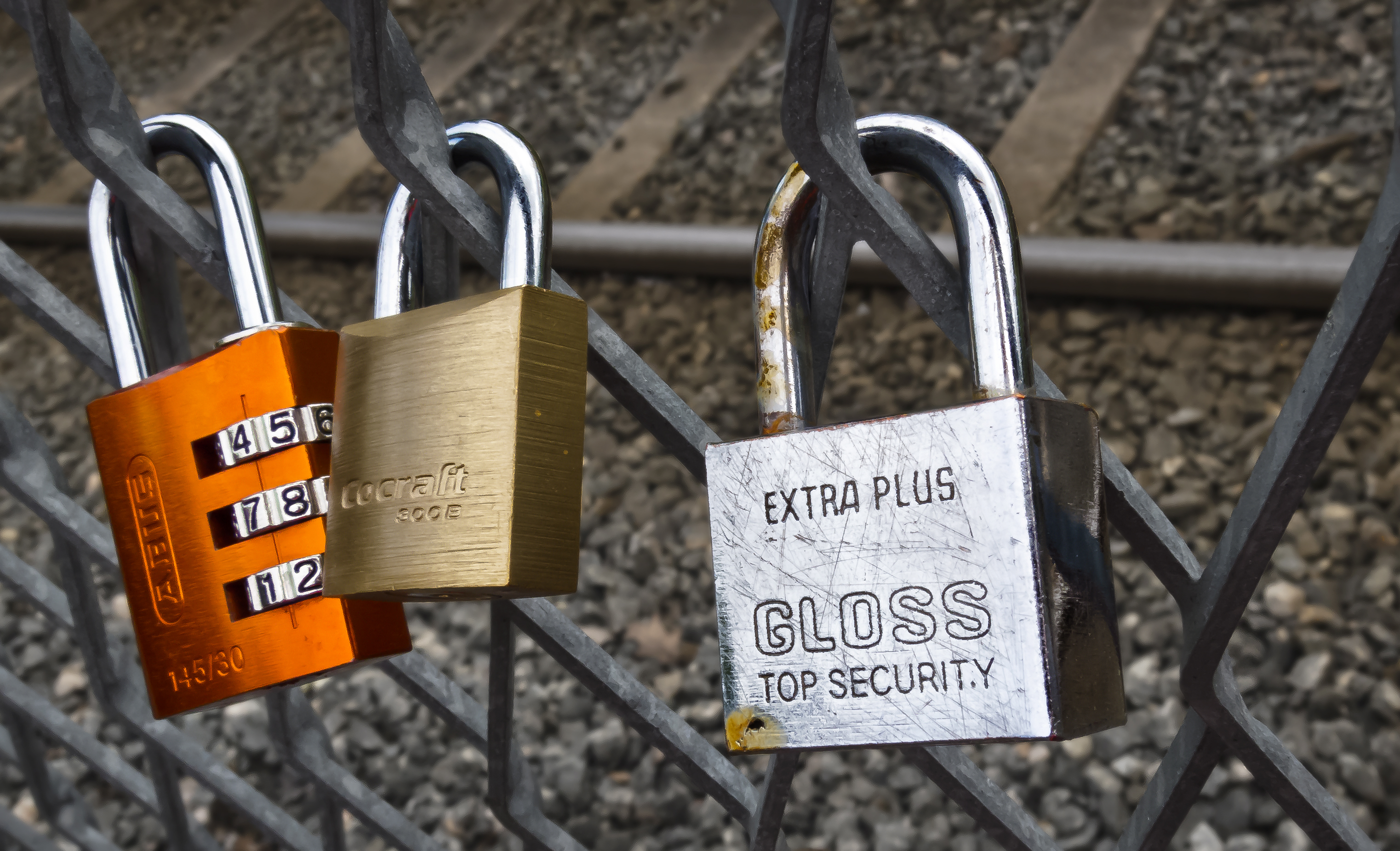 Tre hänglås fastlåsta på ett galler.