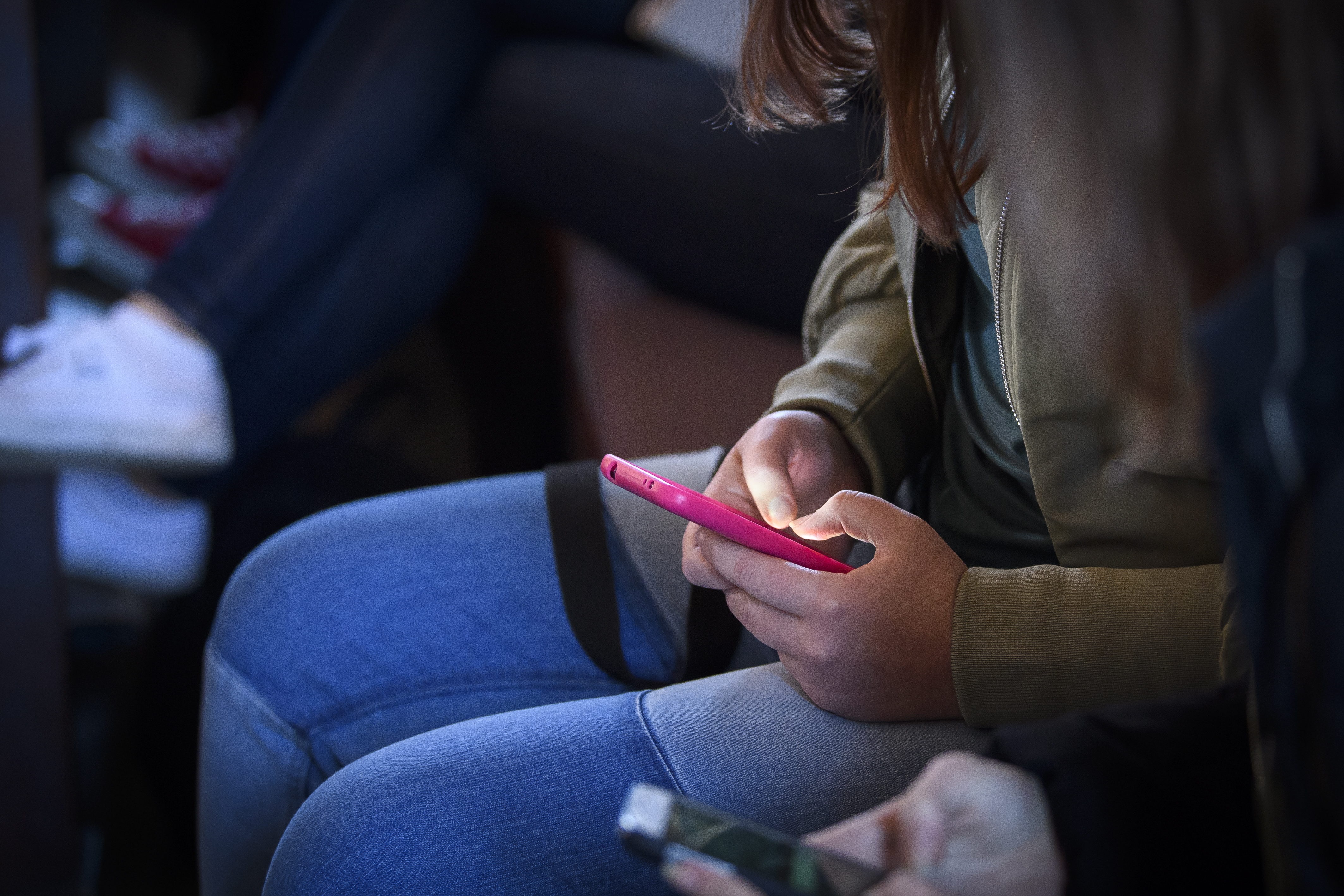 En person sitter och håller på med sin mobiltelefon.
