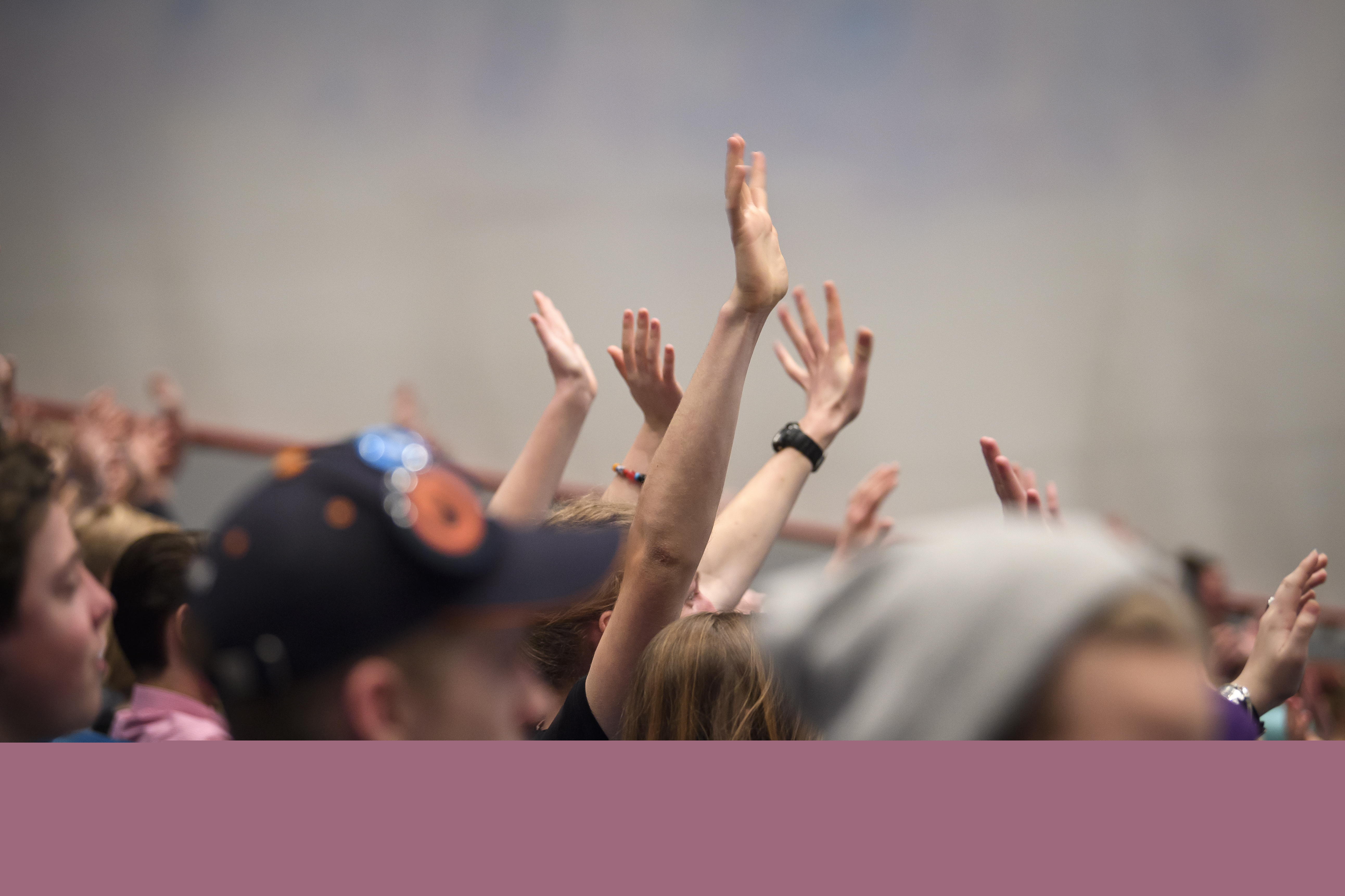 En stor grupp med ungdomar sträcker upp händerna i luften.