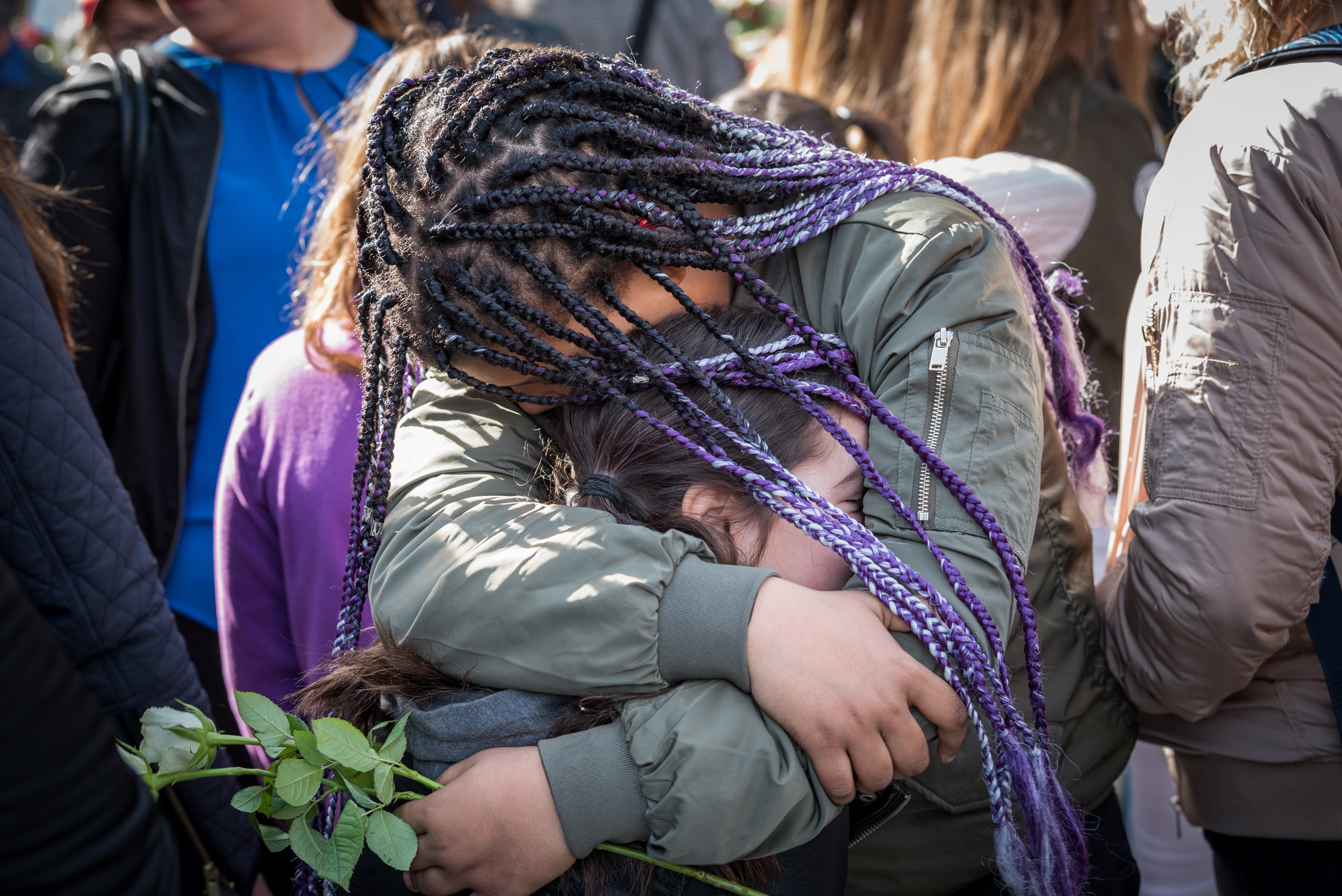 Två flickor i en folkmassa kramar om varandra hårt.