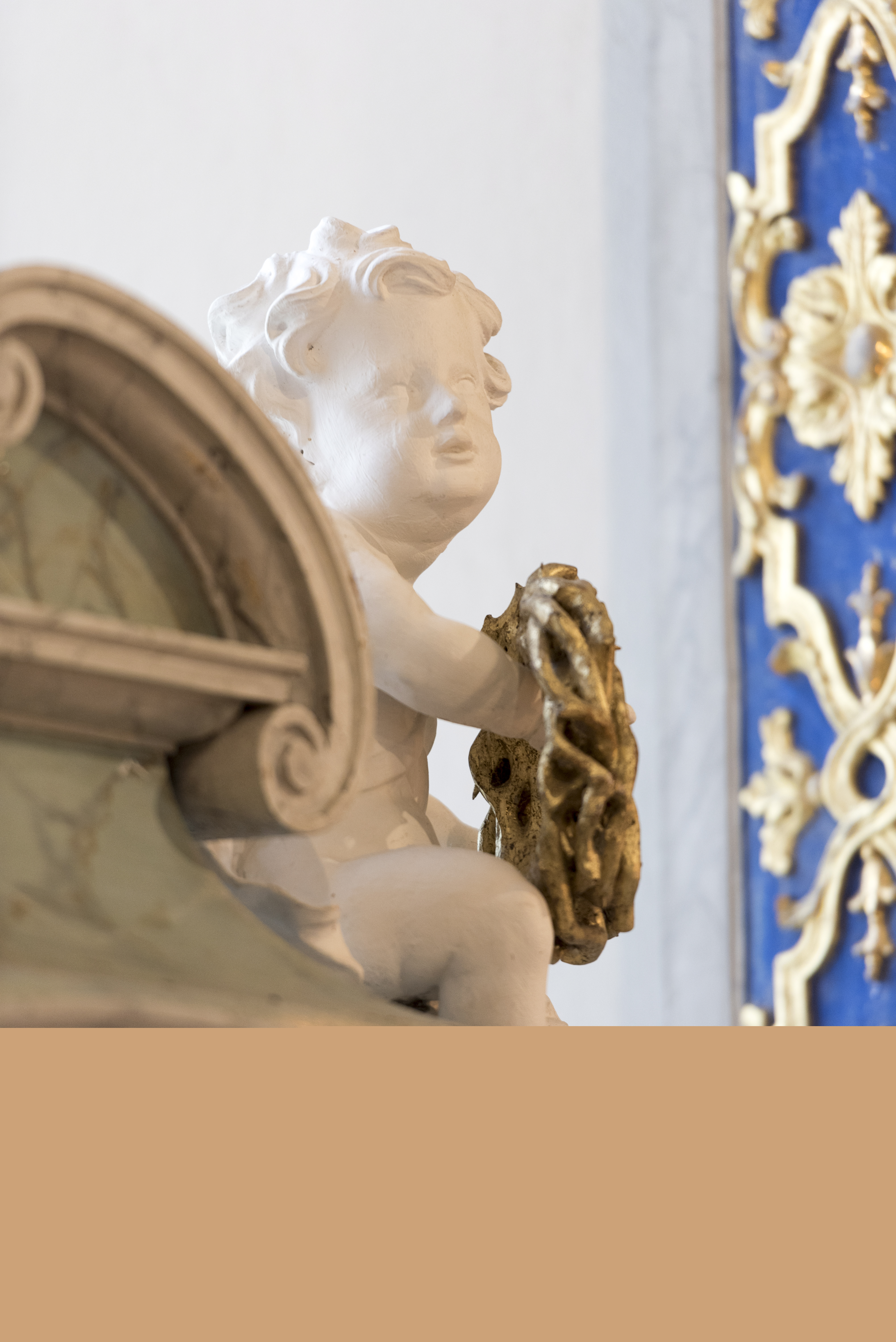 Närbild på en kerub i marmor på ett altare.