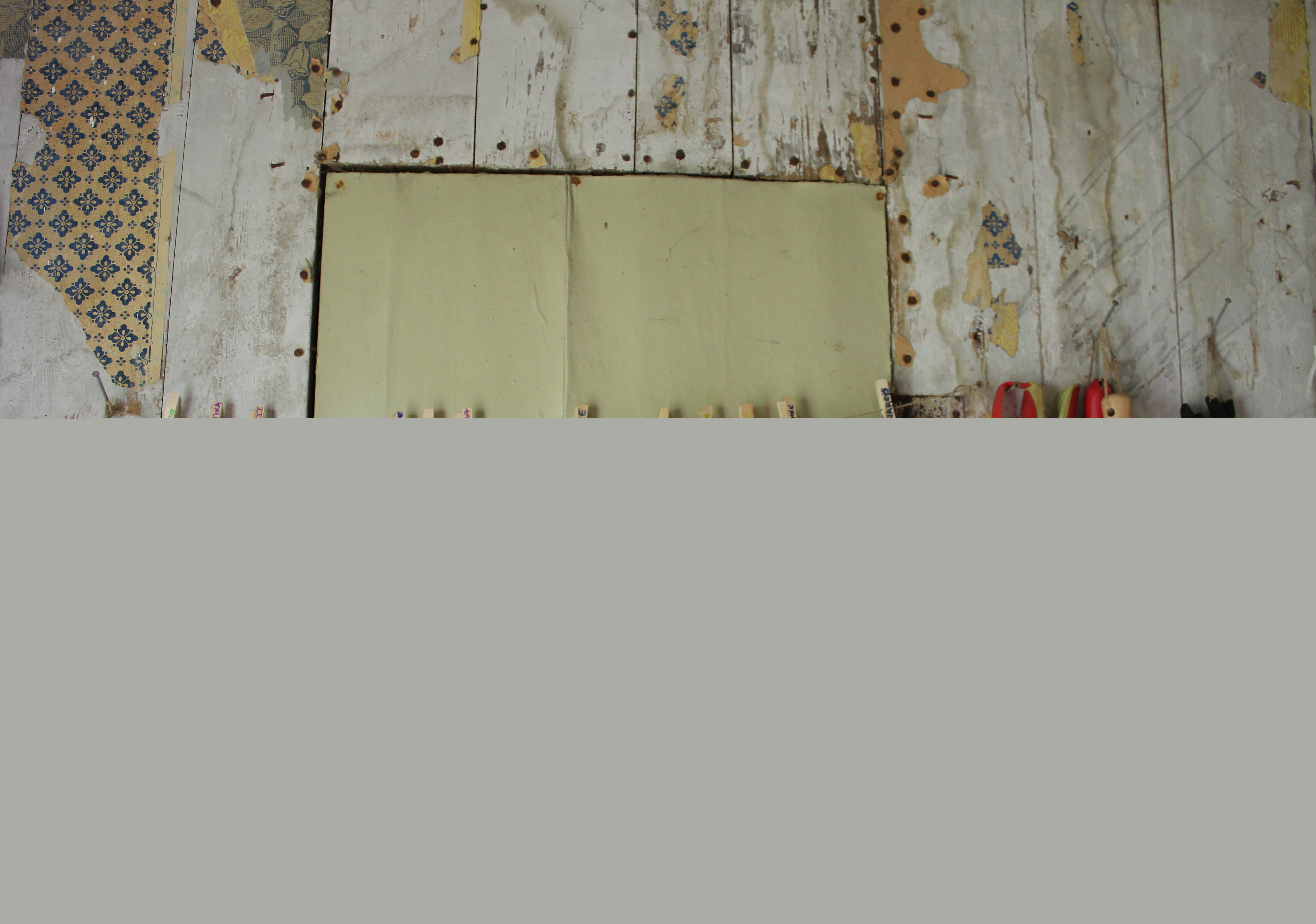 En massa trädgårdshandskar hänger på en tvättlina mot en vägg inomhus.