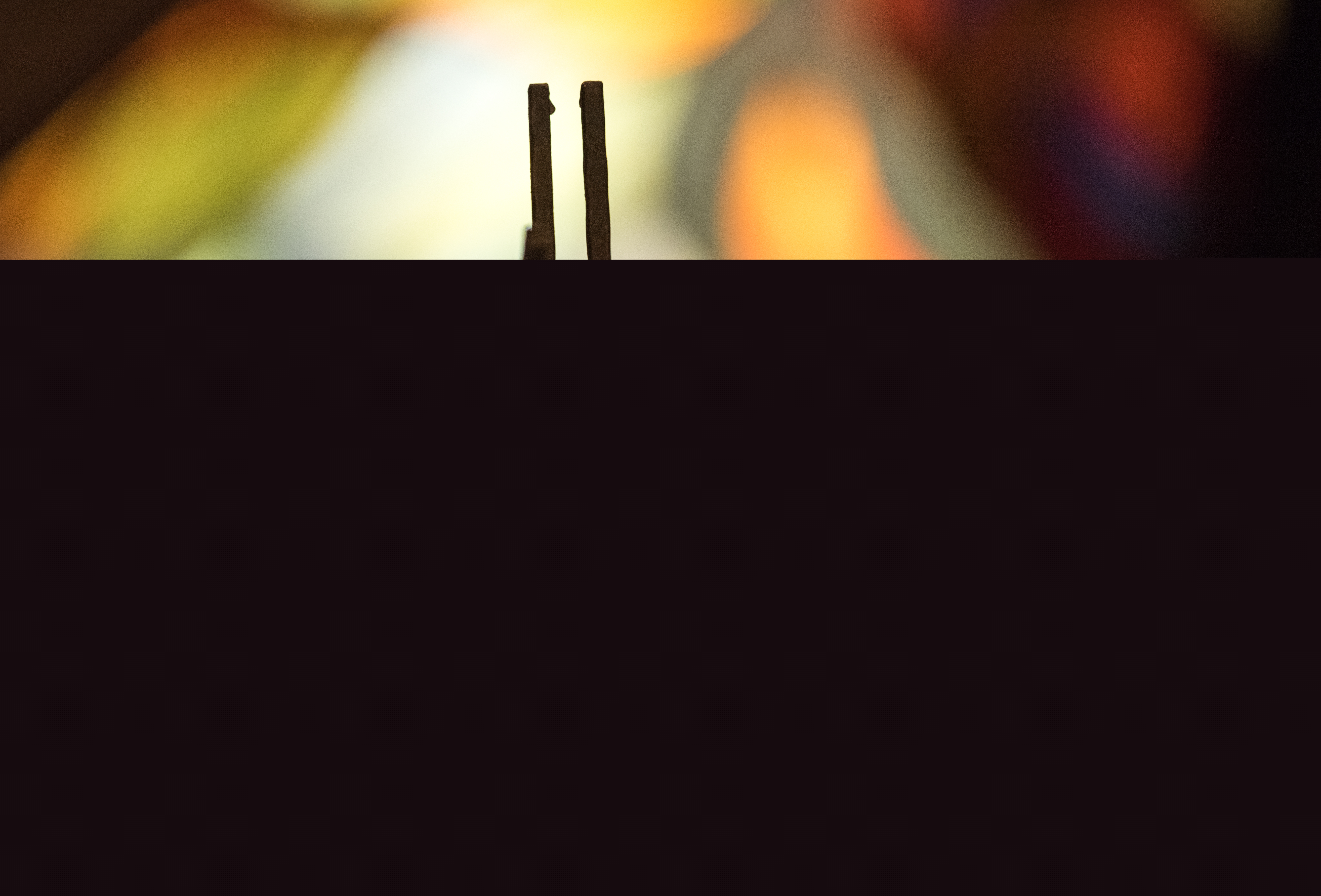 Ett kors i motljus. Suddiga färger syns i bakgrunden.