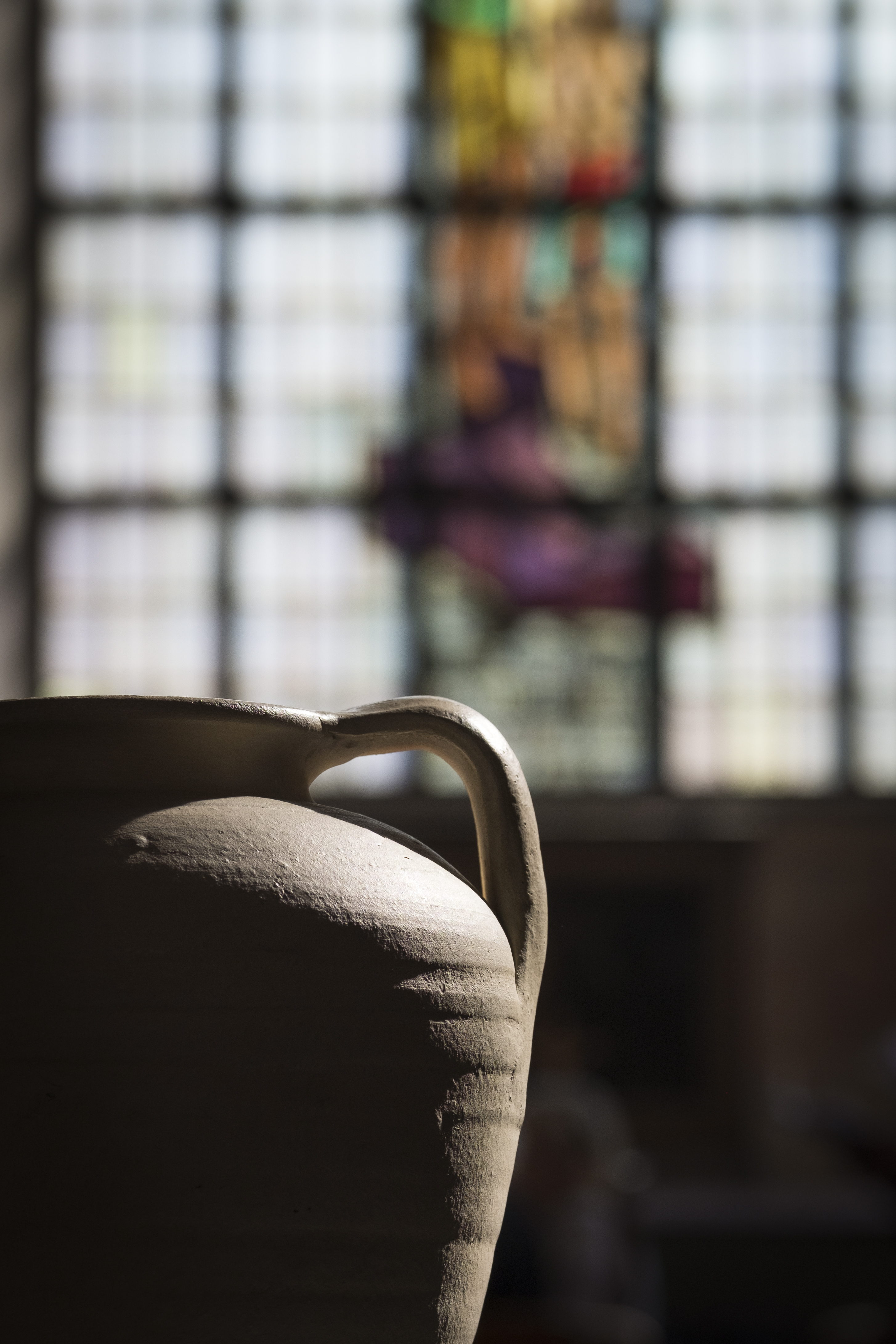 Solen lyser in på en stor kruka. Ett kyrkfönster i bakgrunden.