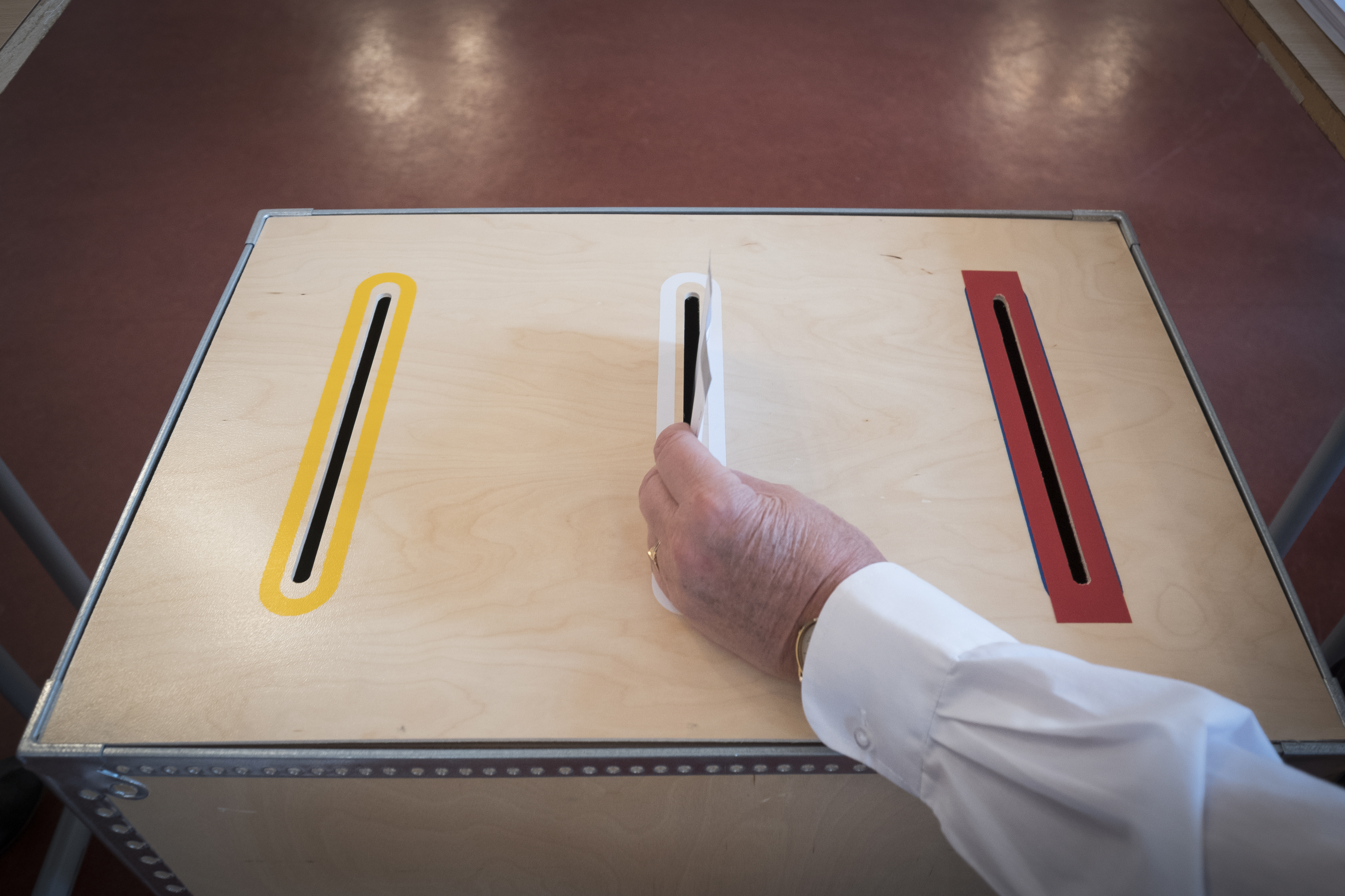 Någon stoppar ett valkuvert i en valurna.