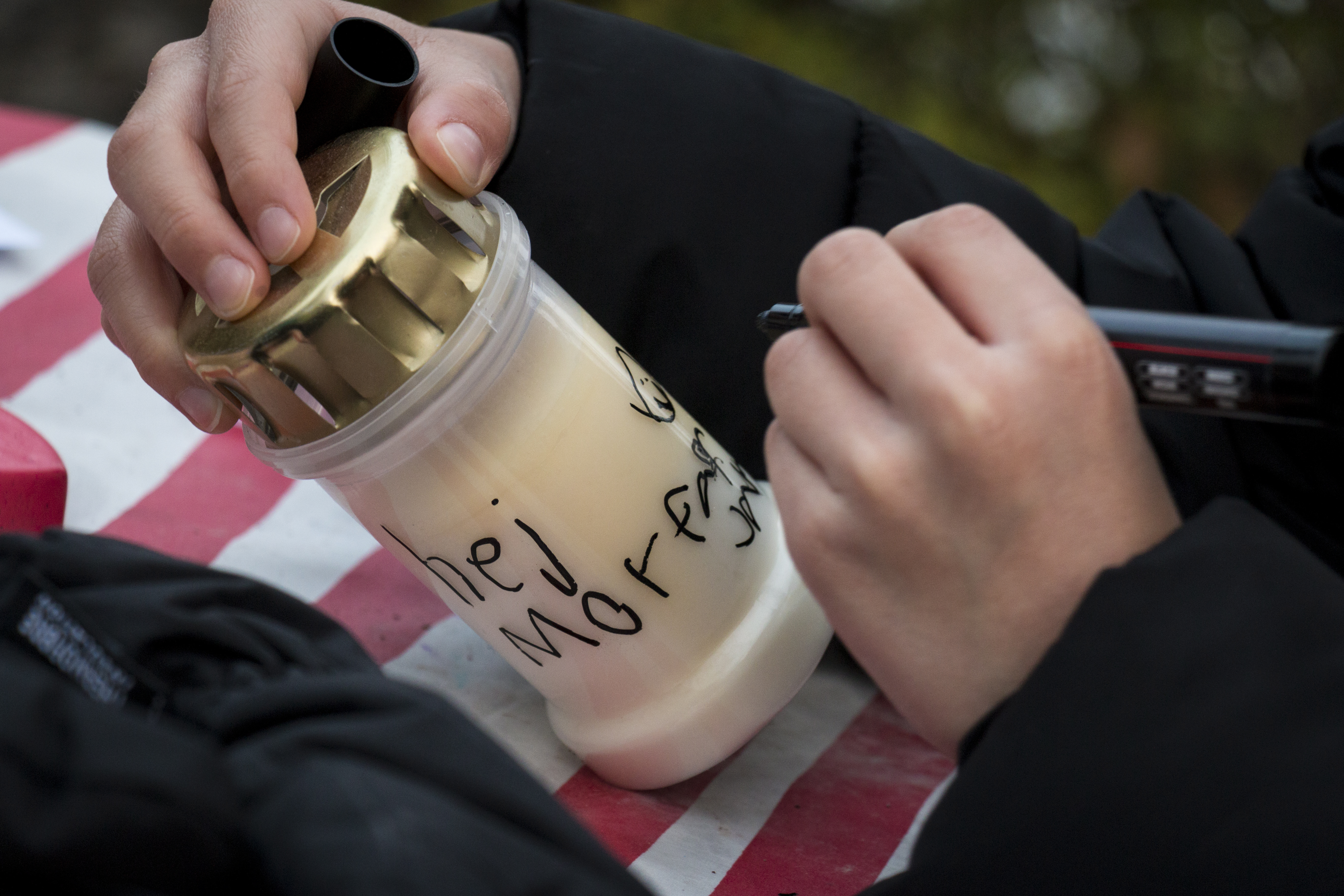 Ett barn skriver en hälsning till sin morfar på ett gravljus.