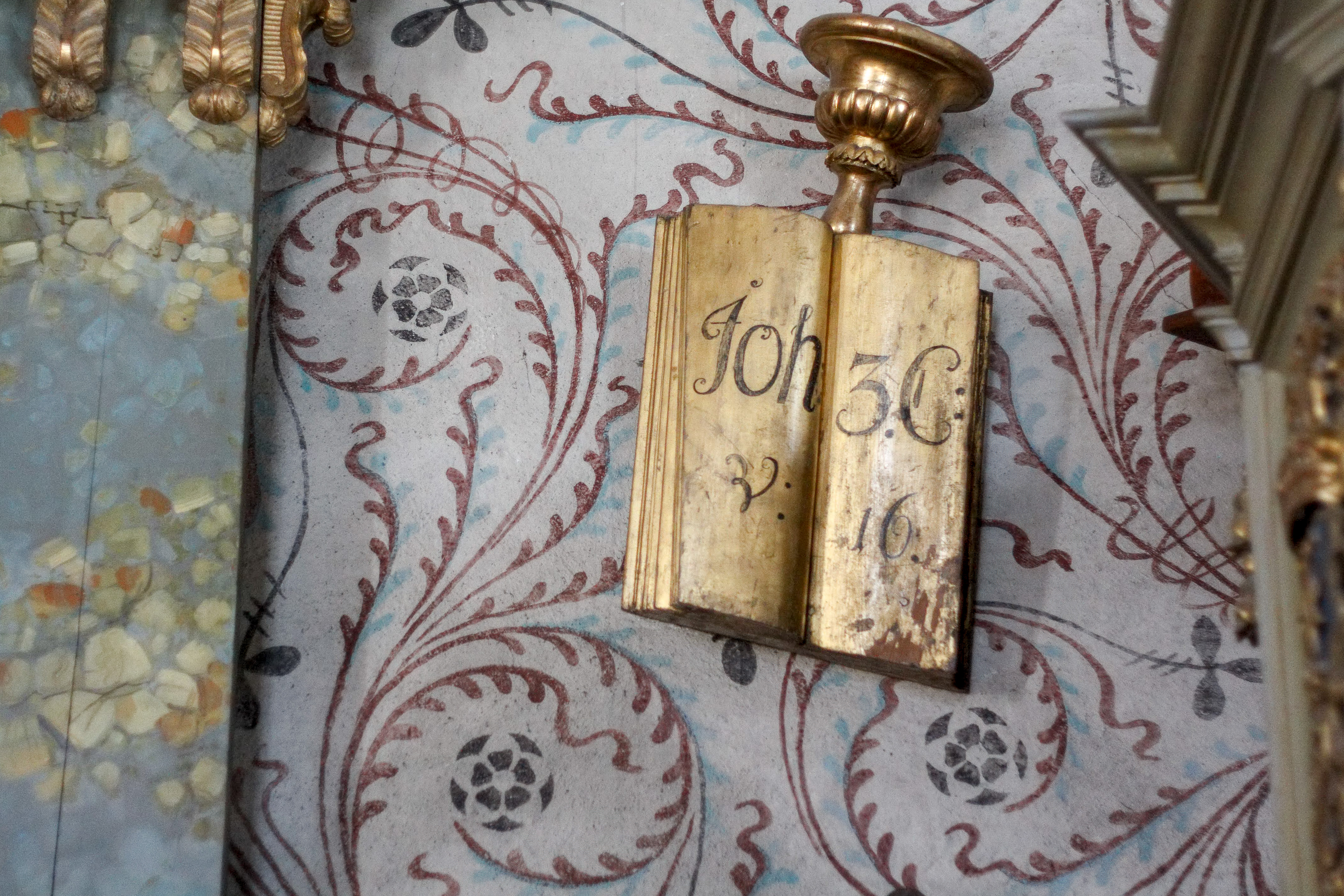 En utsmyckning visar en guldfärgad bok med texten Johannes 3:16 på uppslaget.