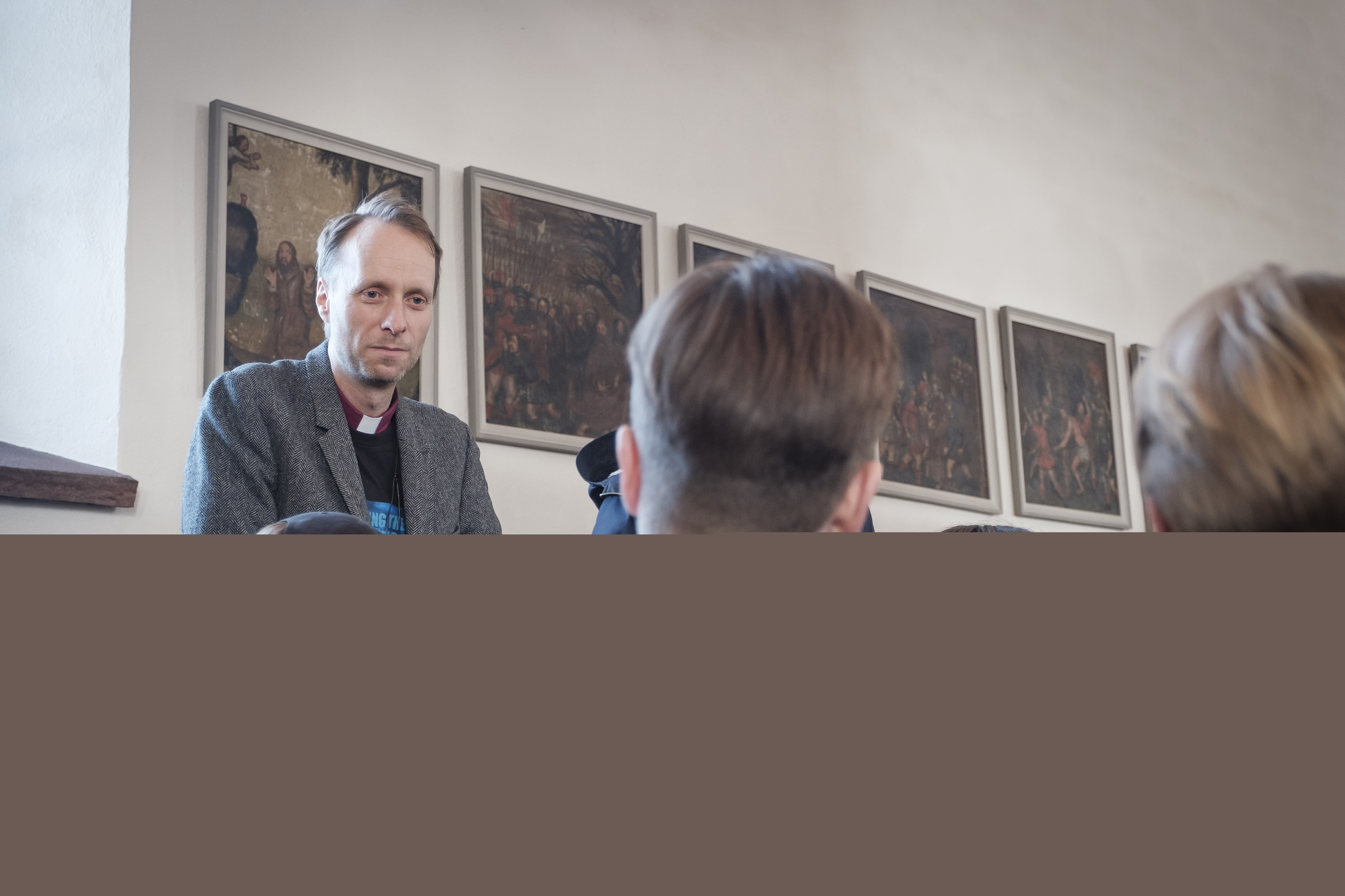 Biskop Mikael Mogren står vid några ungdomar som sitter i kyrkbänkarna.