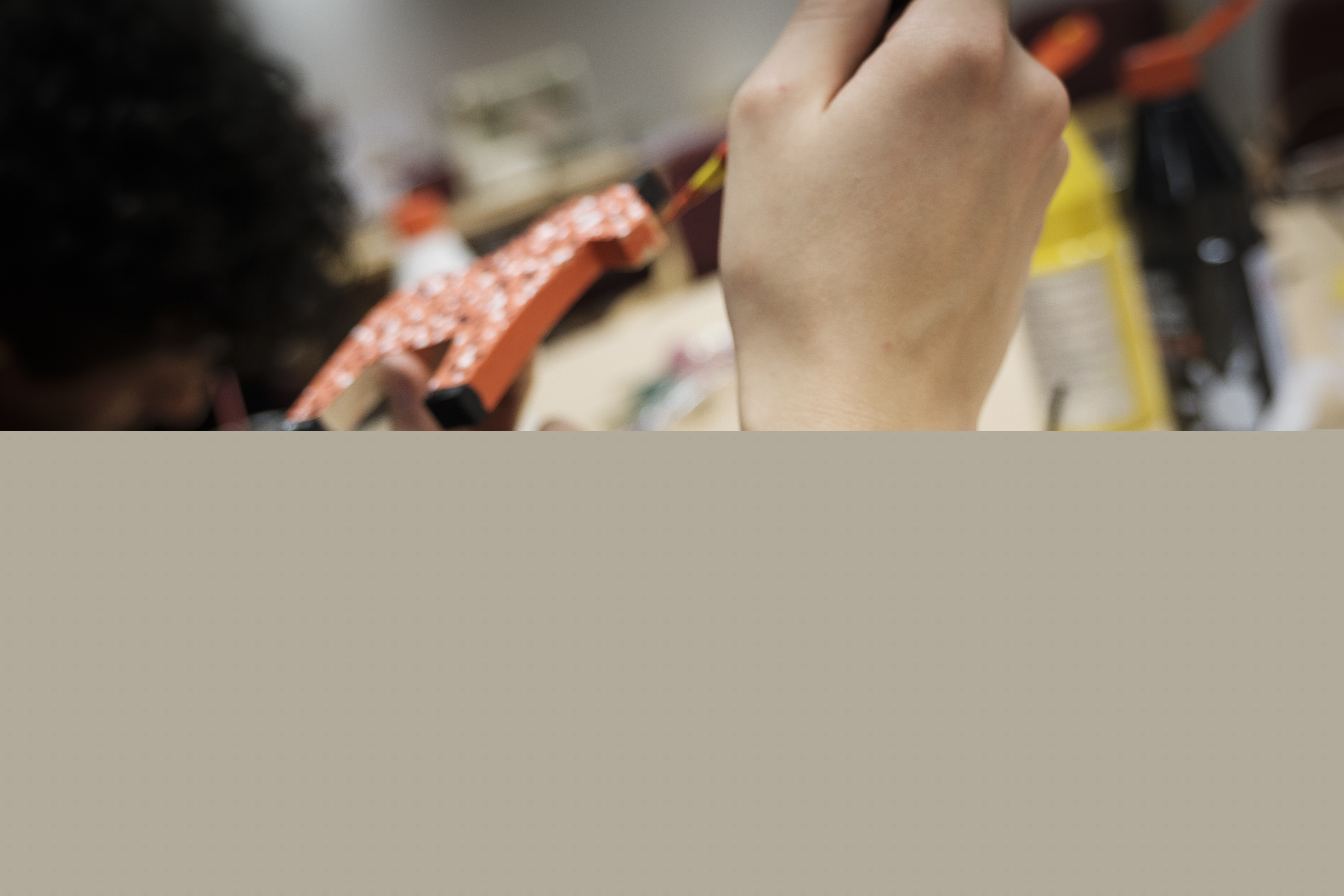 En person med ett korsarmband målar en liten trähäst.