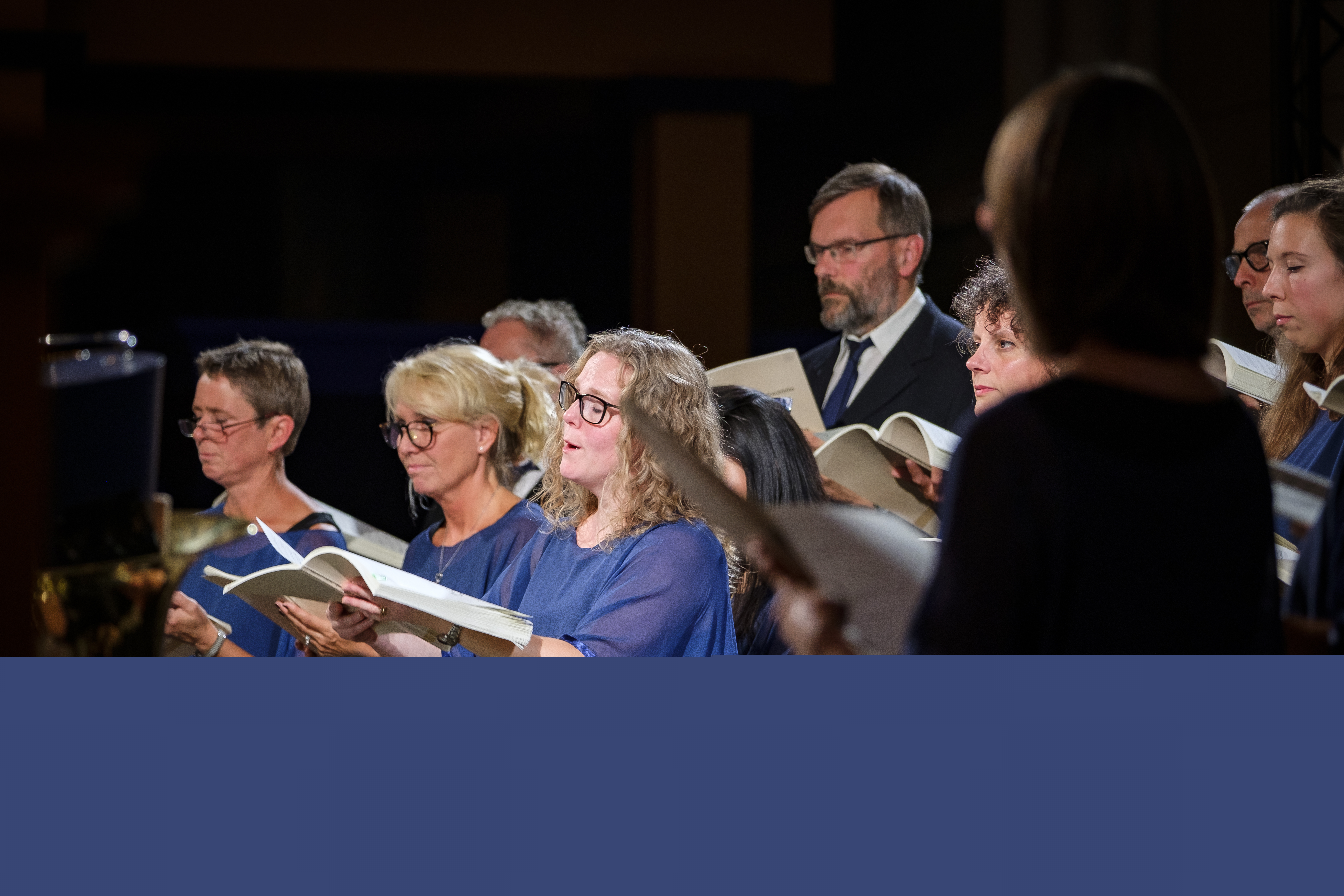 En blandad kyrkokör i matchande blå färger sjunger.