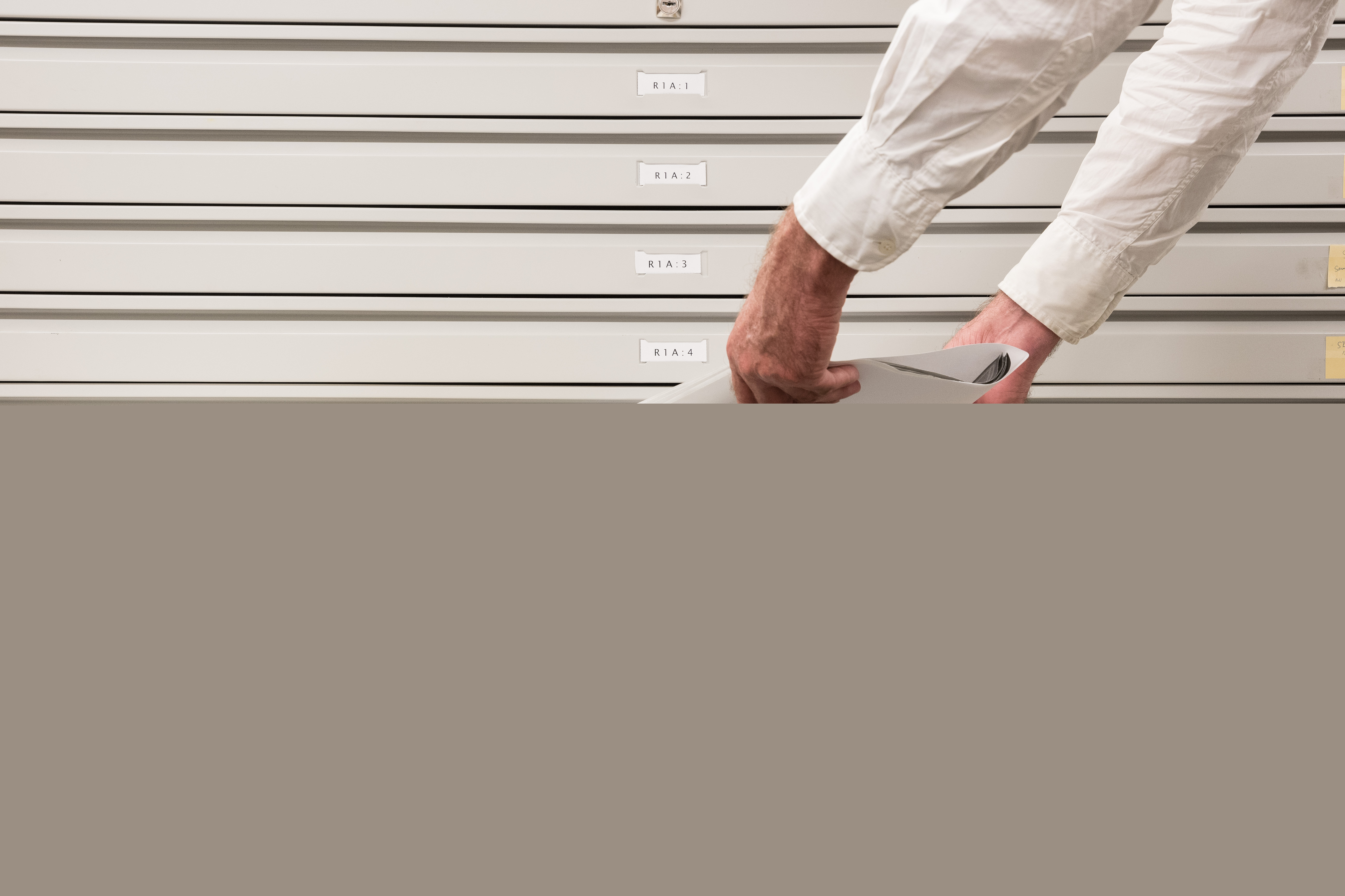 Någon lägger ner papper i en arkivlåda.