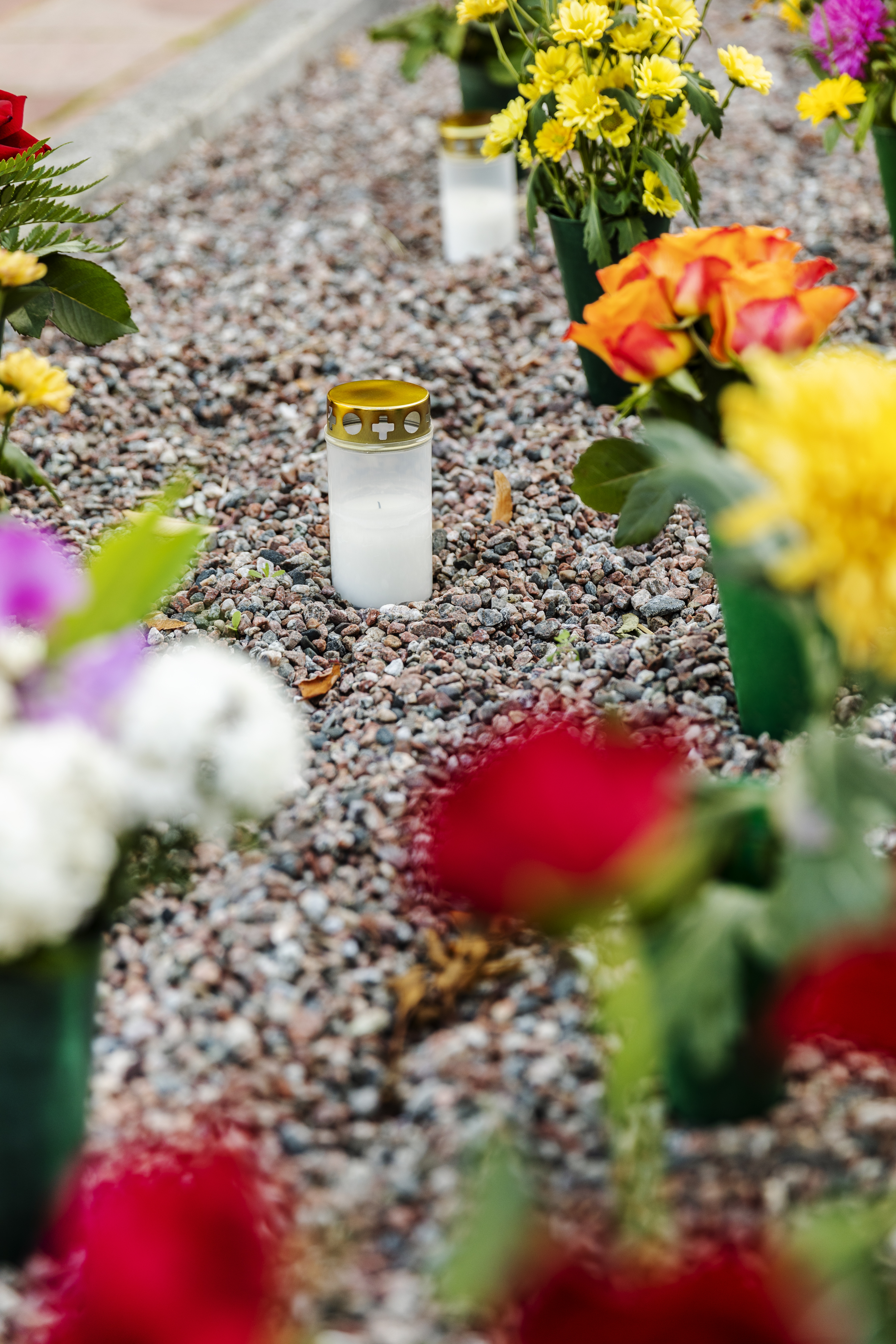 En massa blombuketter och gravljus står på en minneslund.