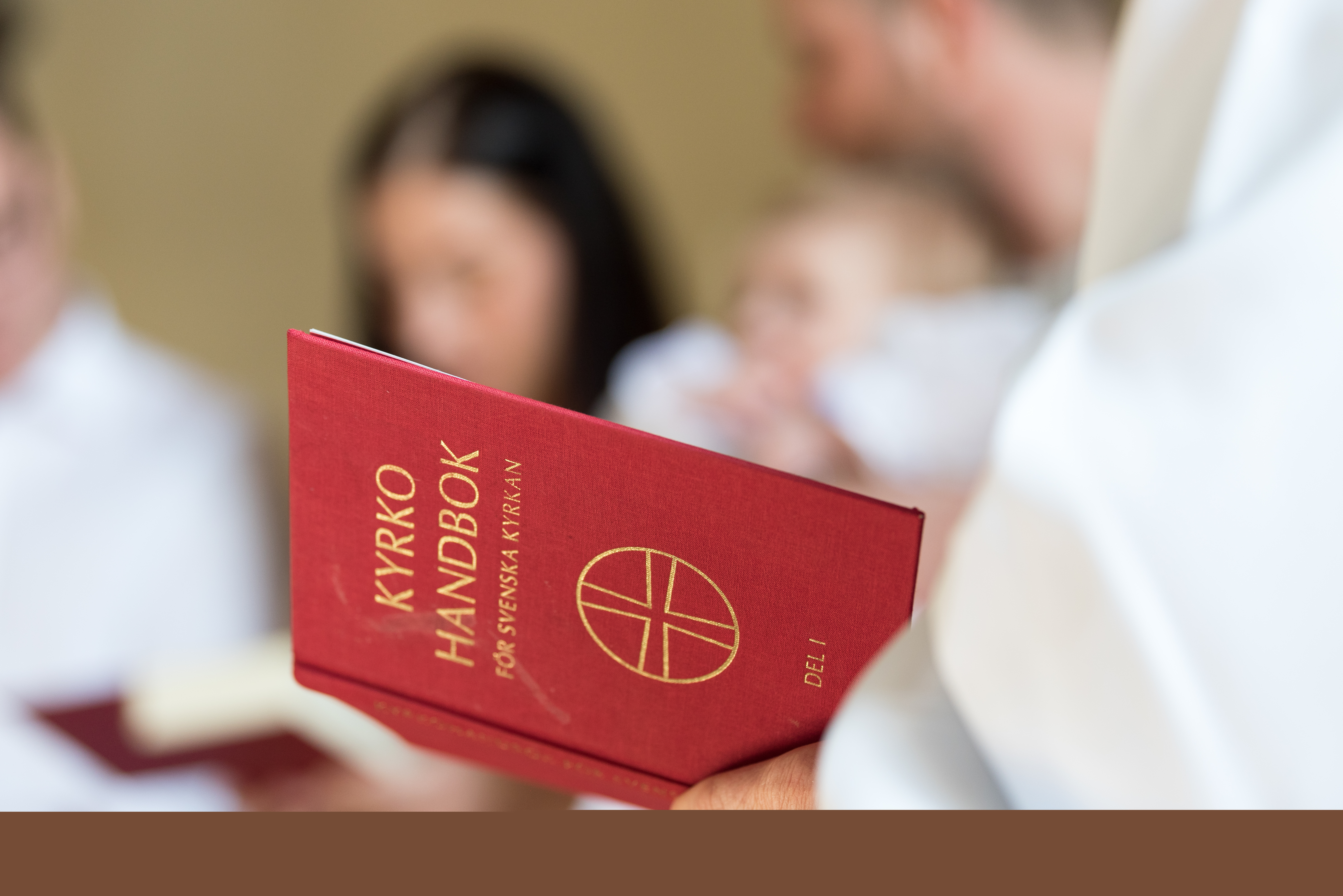 En vitklädd person håller i en kyrkohandbok.