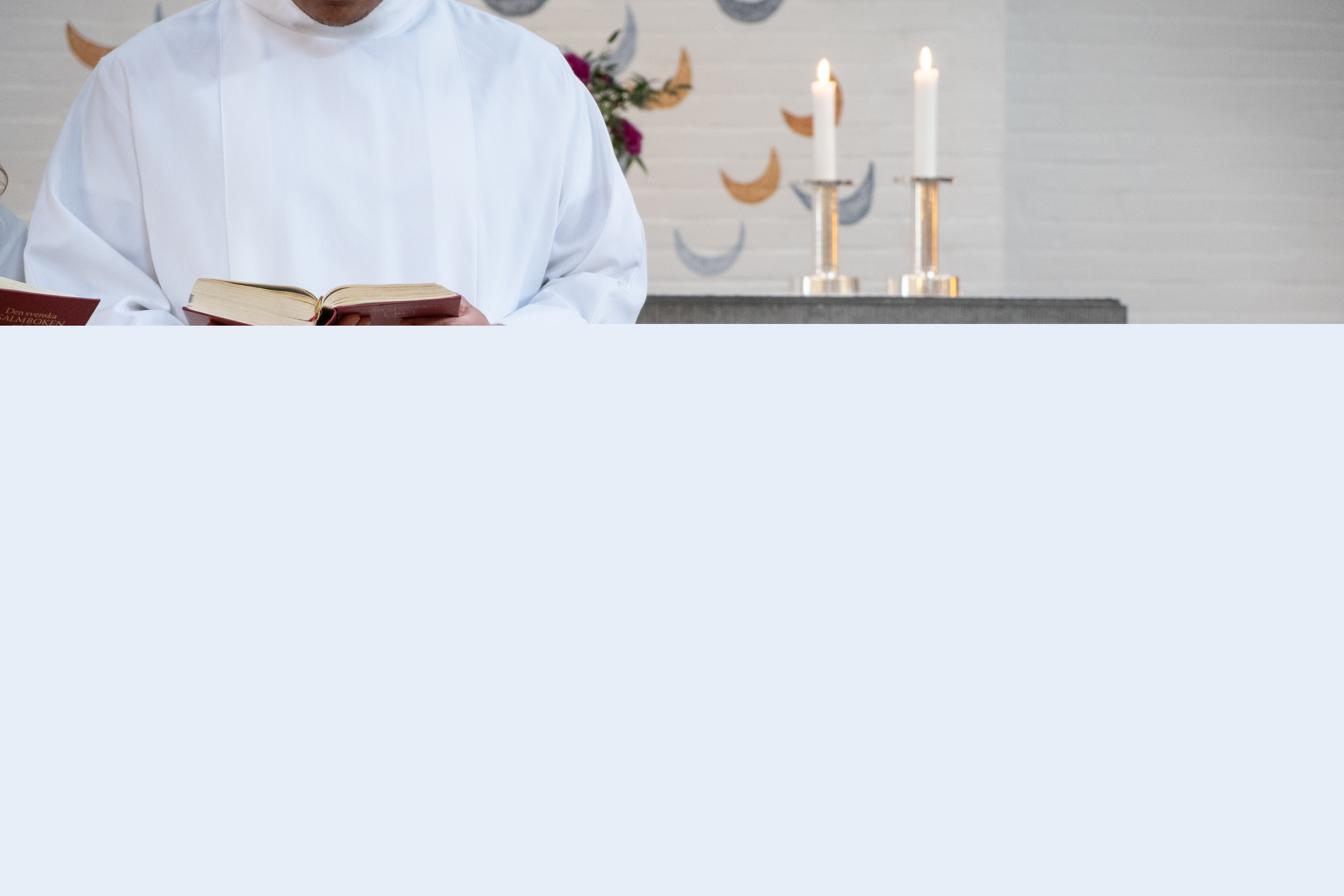 En man i vit kåpa står vid en dopfunt.