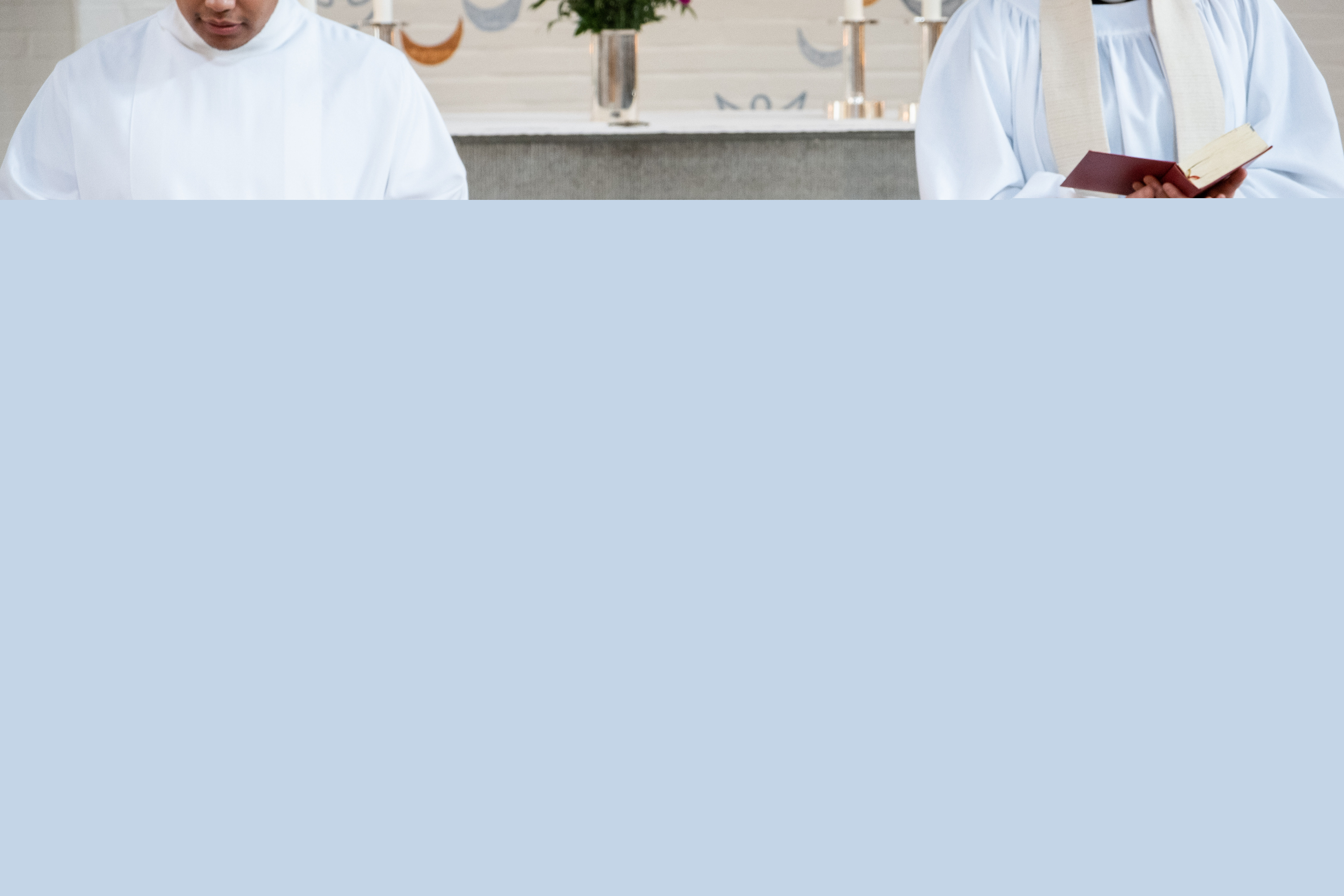 En präst och en man i vit dopkåpa står på varsin sida om en dopfunt.