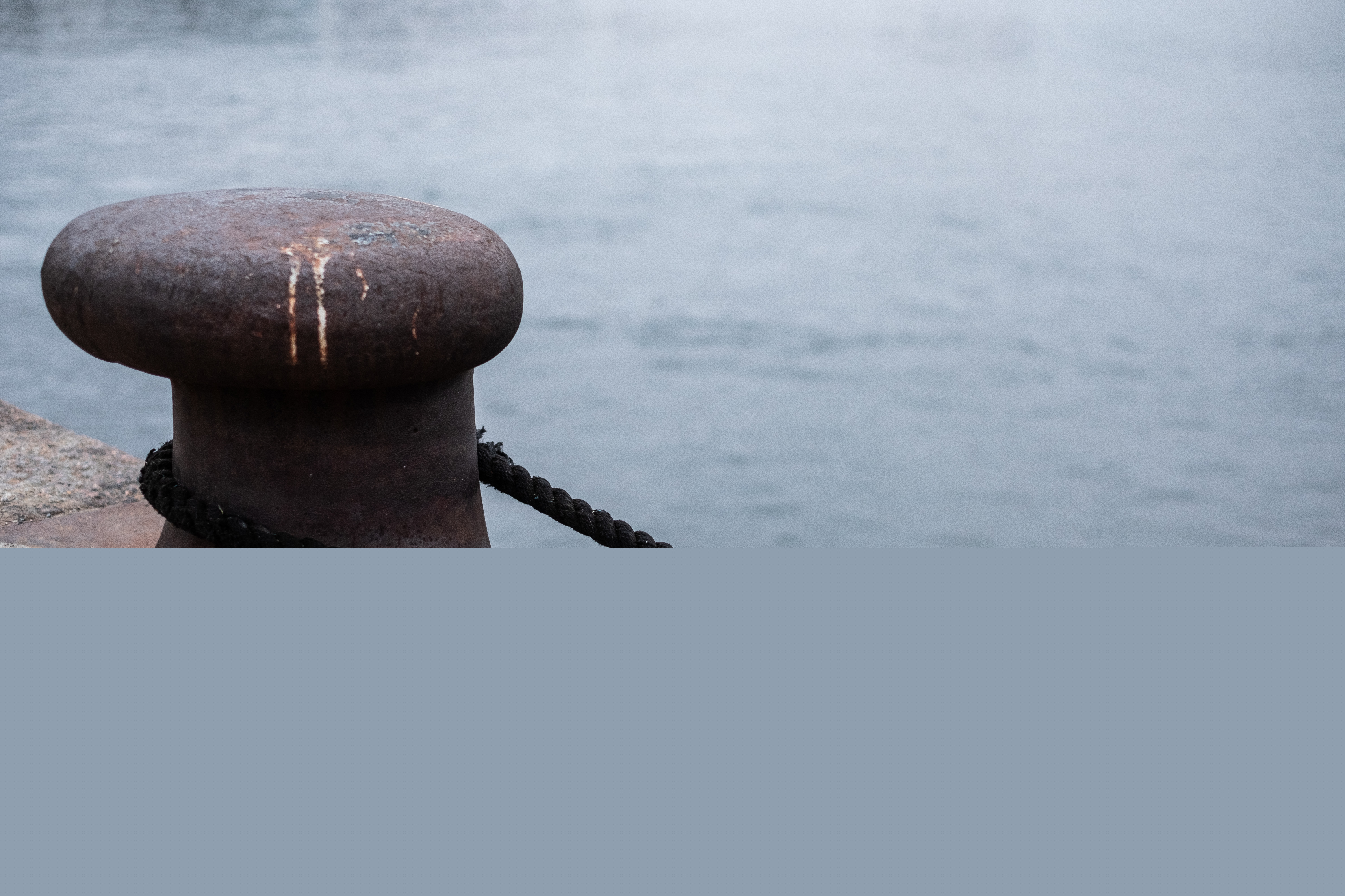 En svart tross har lagts runt en pollare vid kajkanten.