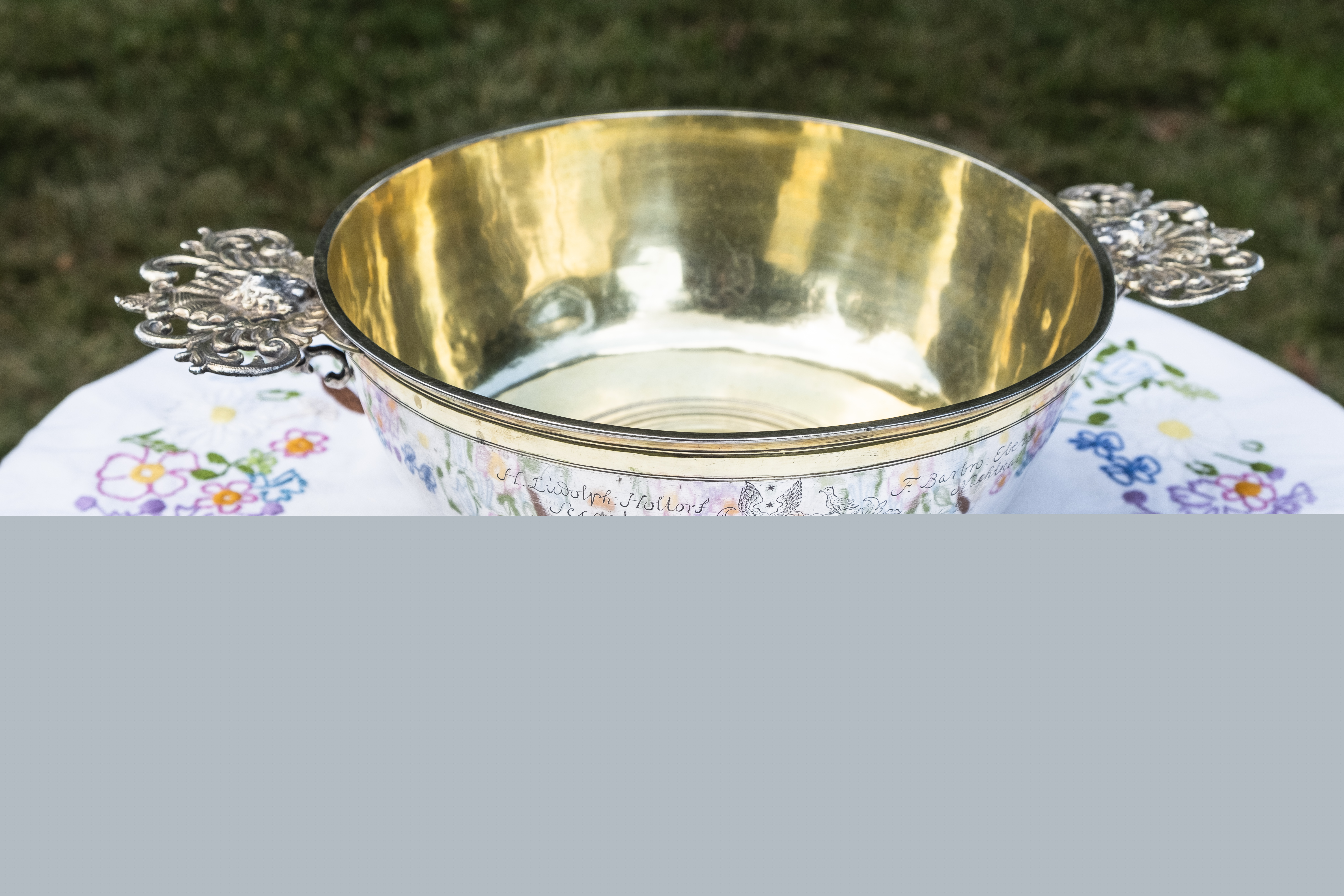 En dopfunt står utomhus på ett bord med en broderad duk.