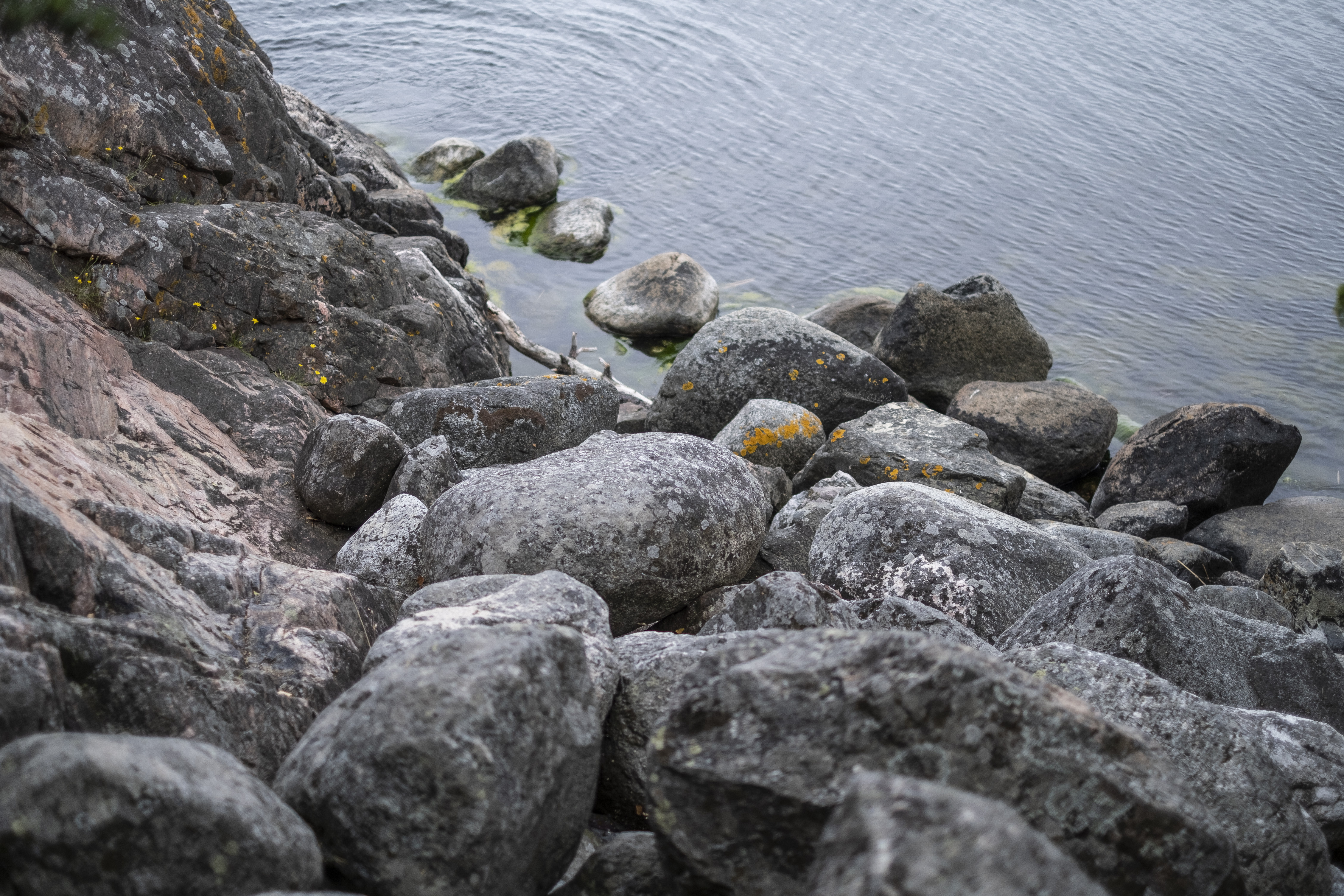 Lösa stenar på klippan ner mot vattnet.