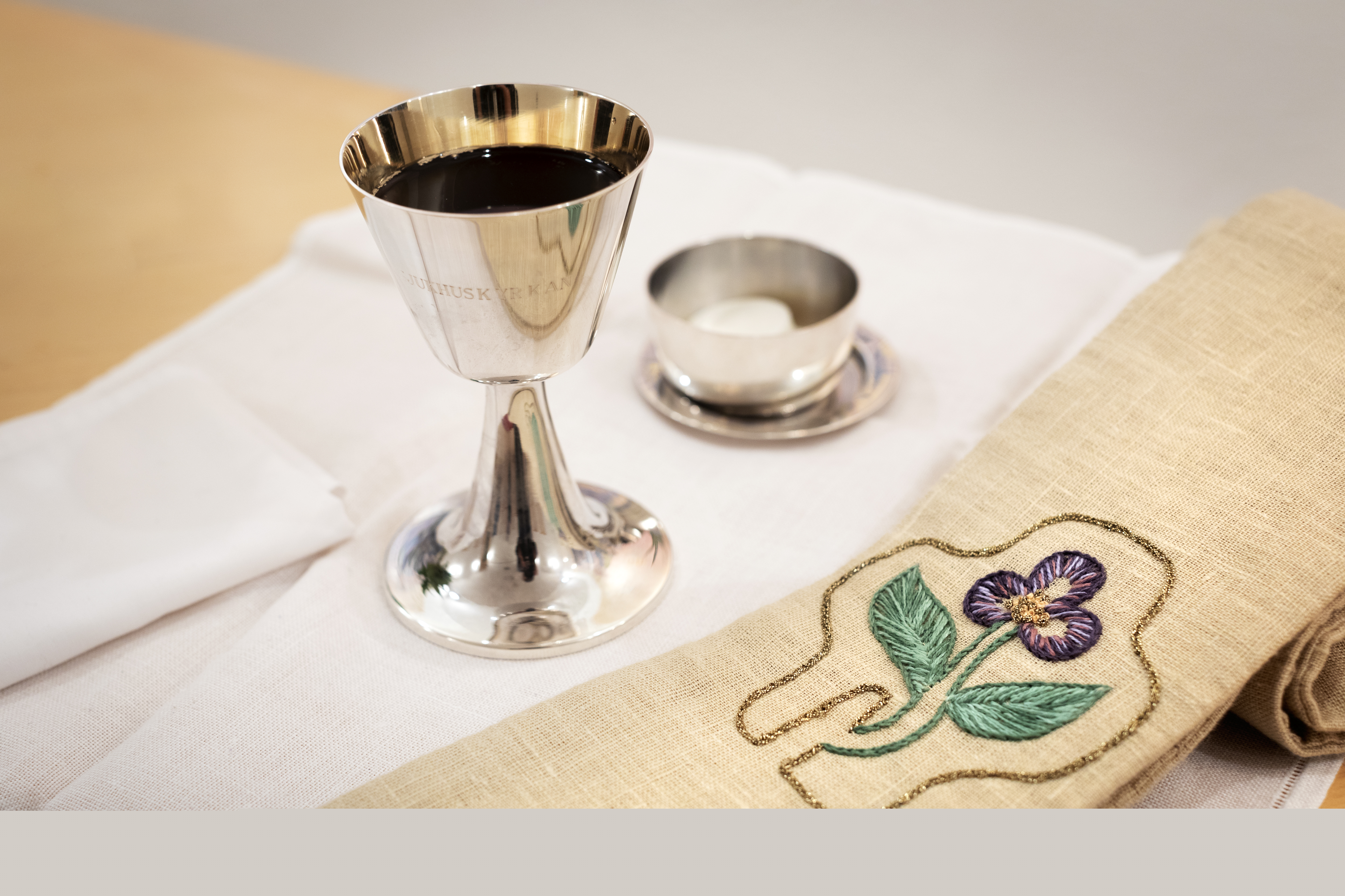 En silverkalk med vin står på ett bord.