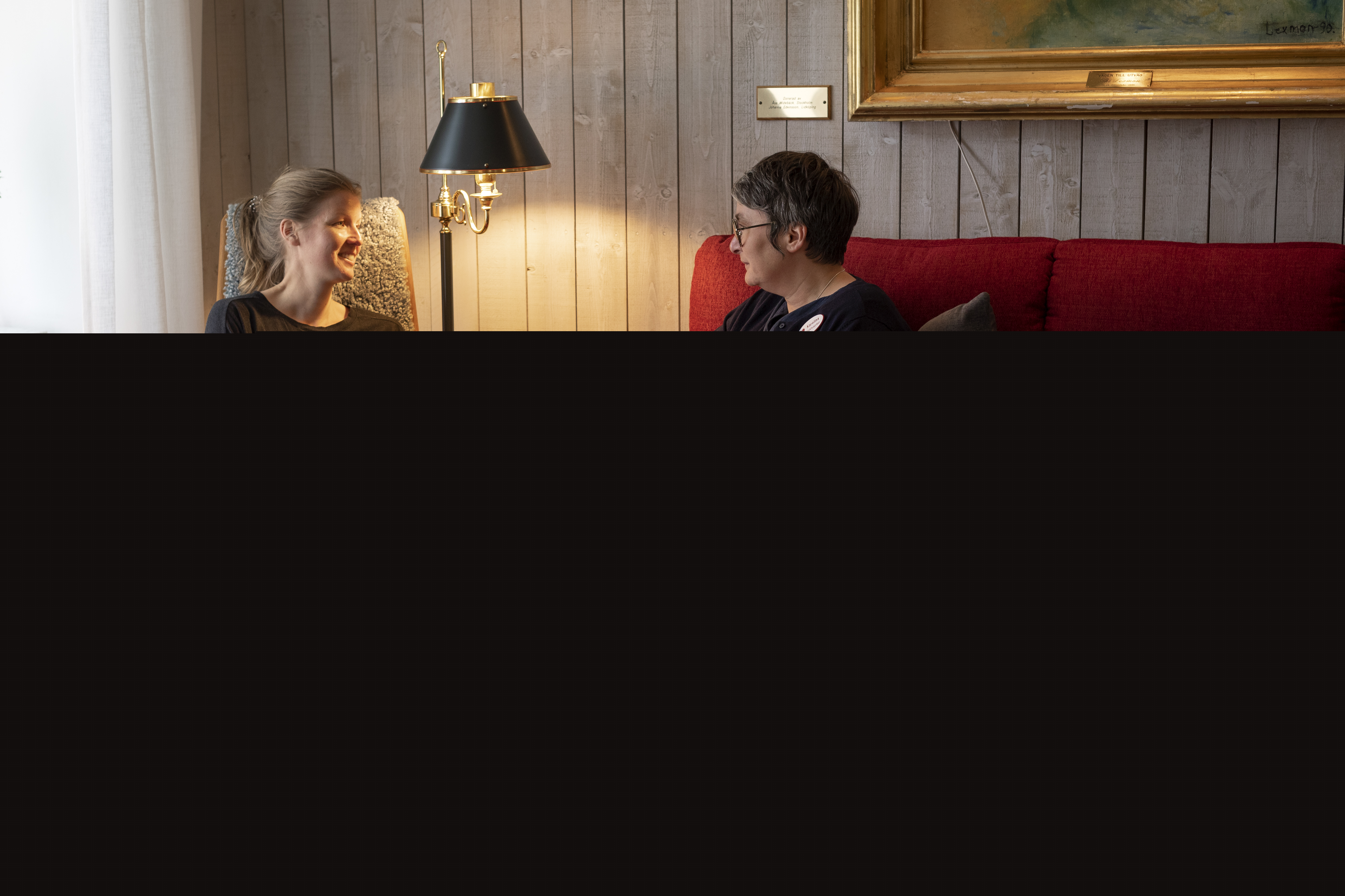 Två kvinnor sitter och samtalar i ett vardagsrum.