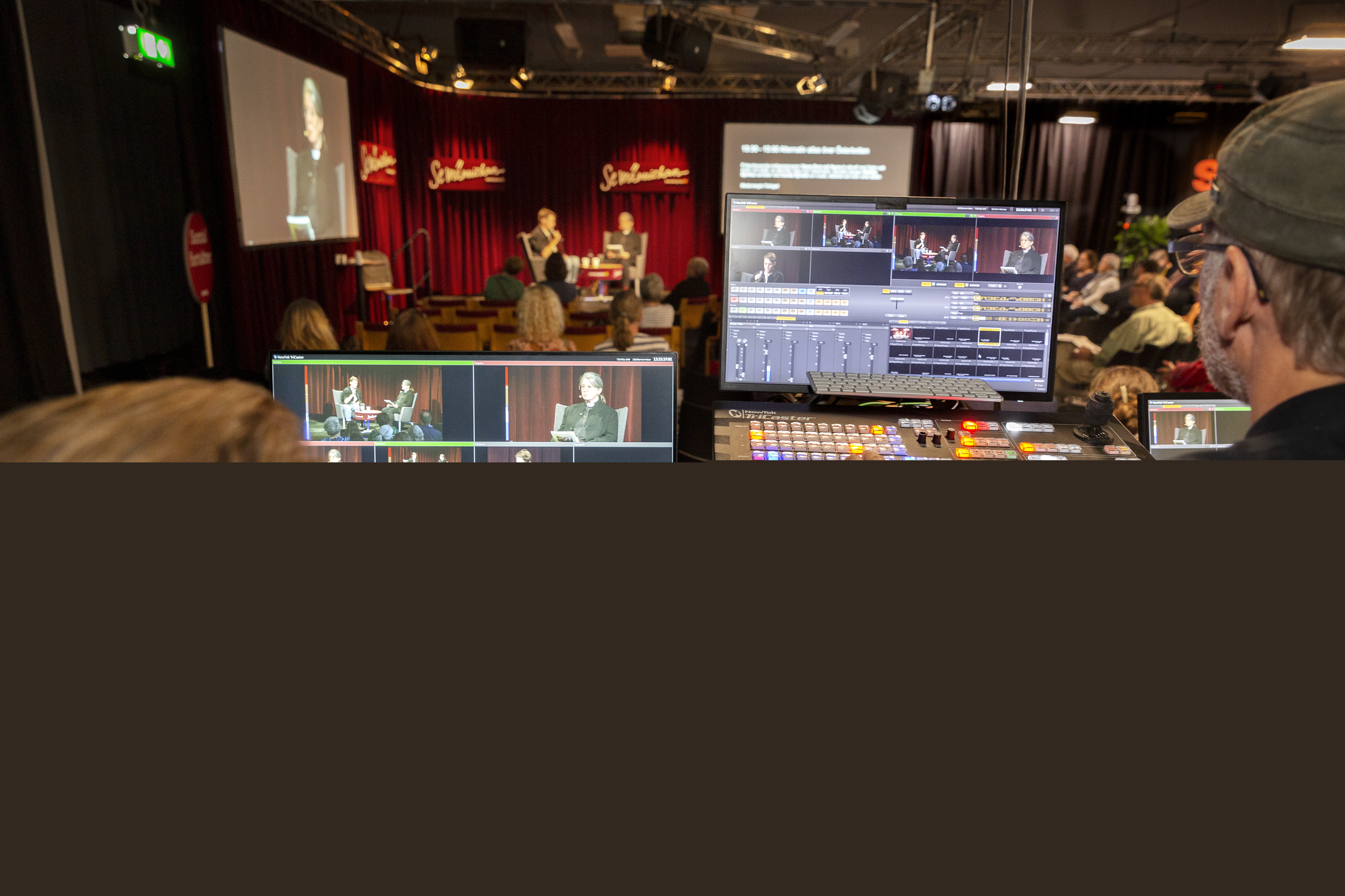 Två studiotekniker övervakar inspelningen av ett samtal på en scen.