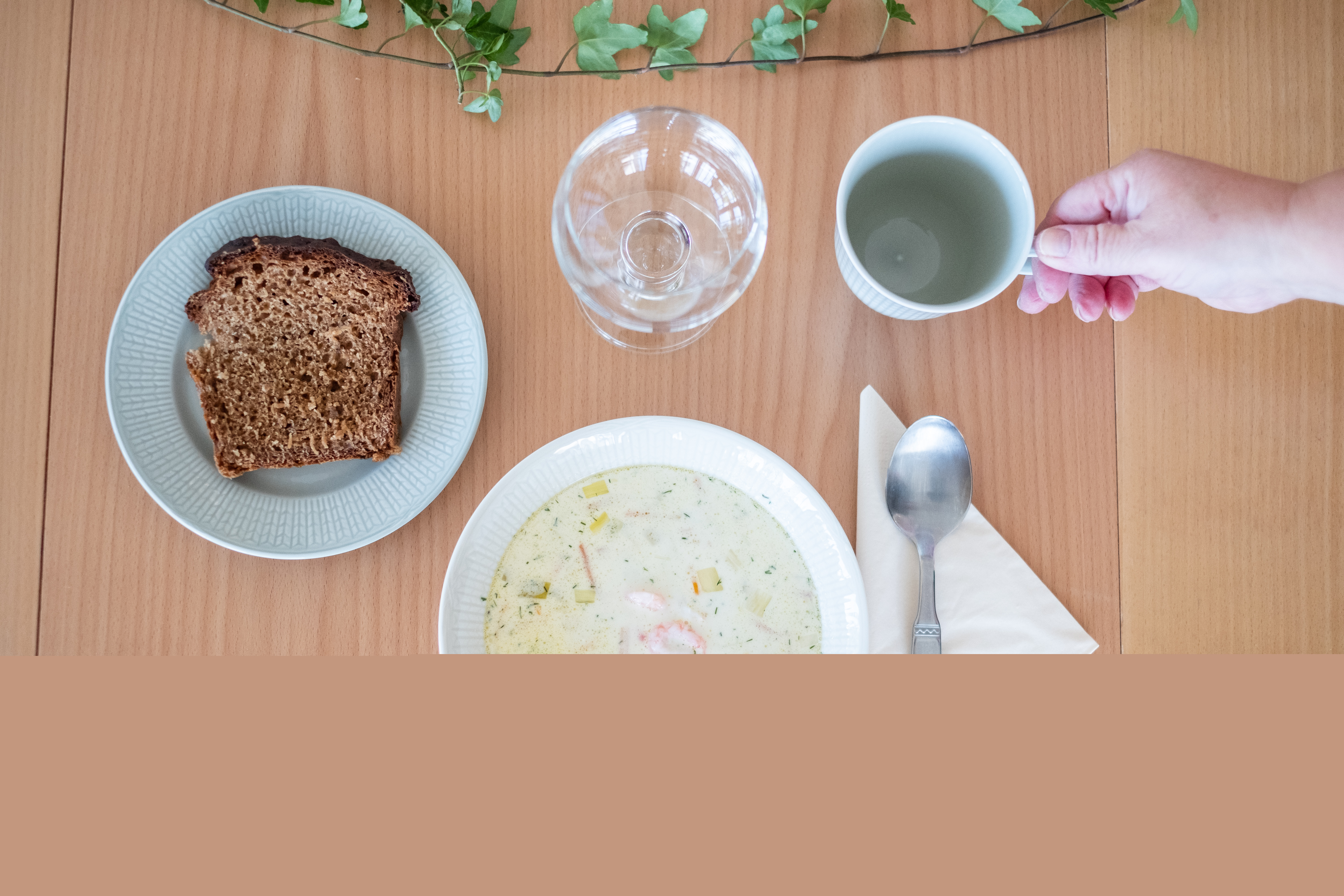 En skål soppa och en brödbit står framdukat på ett bord.