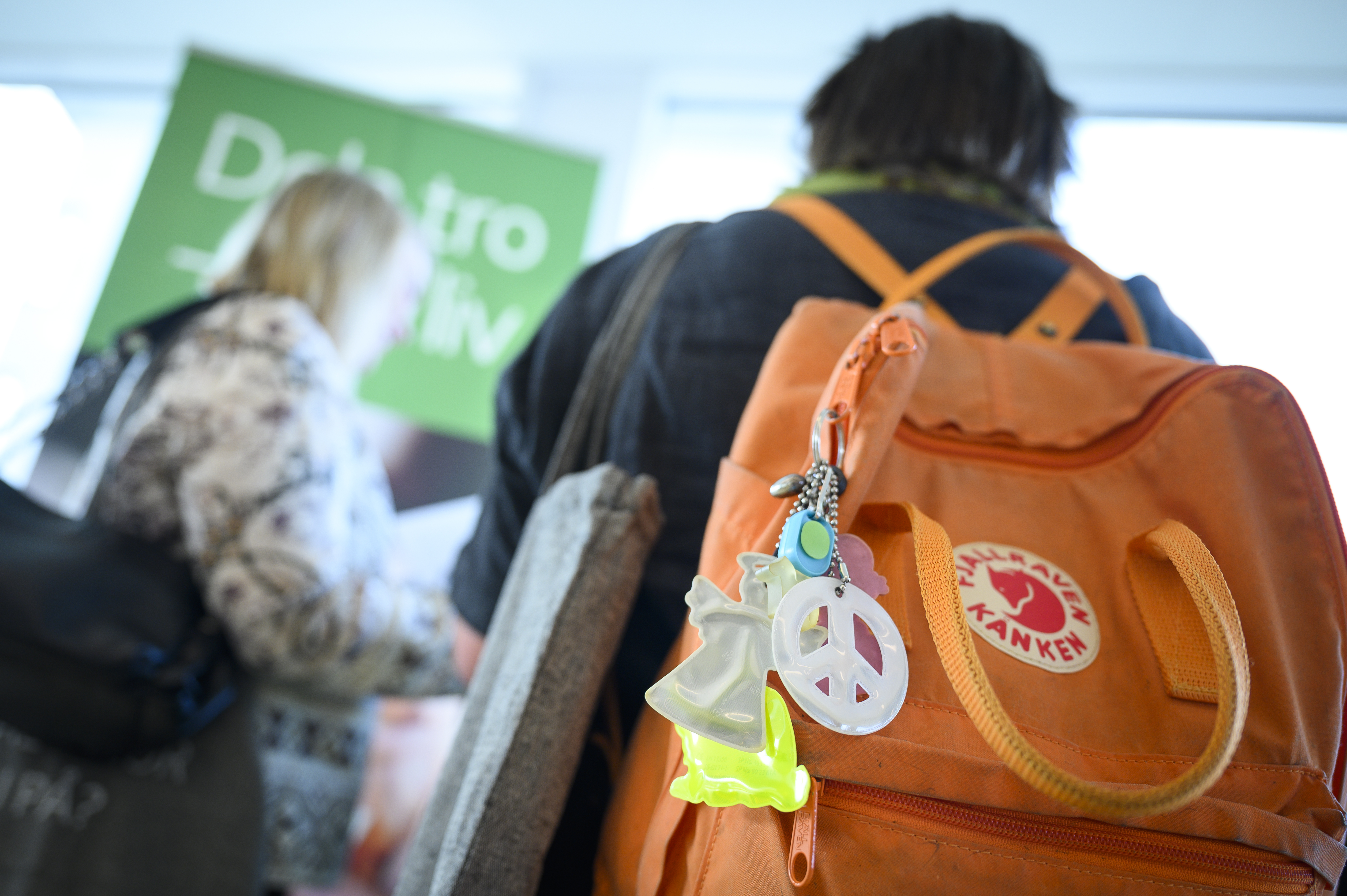 Två personer på konferens eller mässa. Personen närmast kameran har en ryggsäck med olika reflexer hängande.