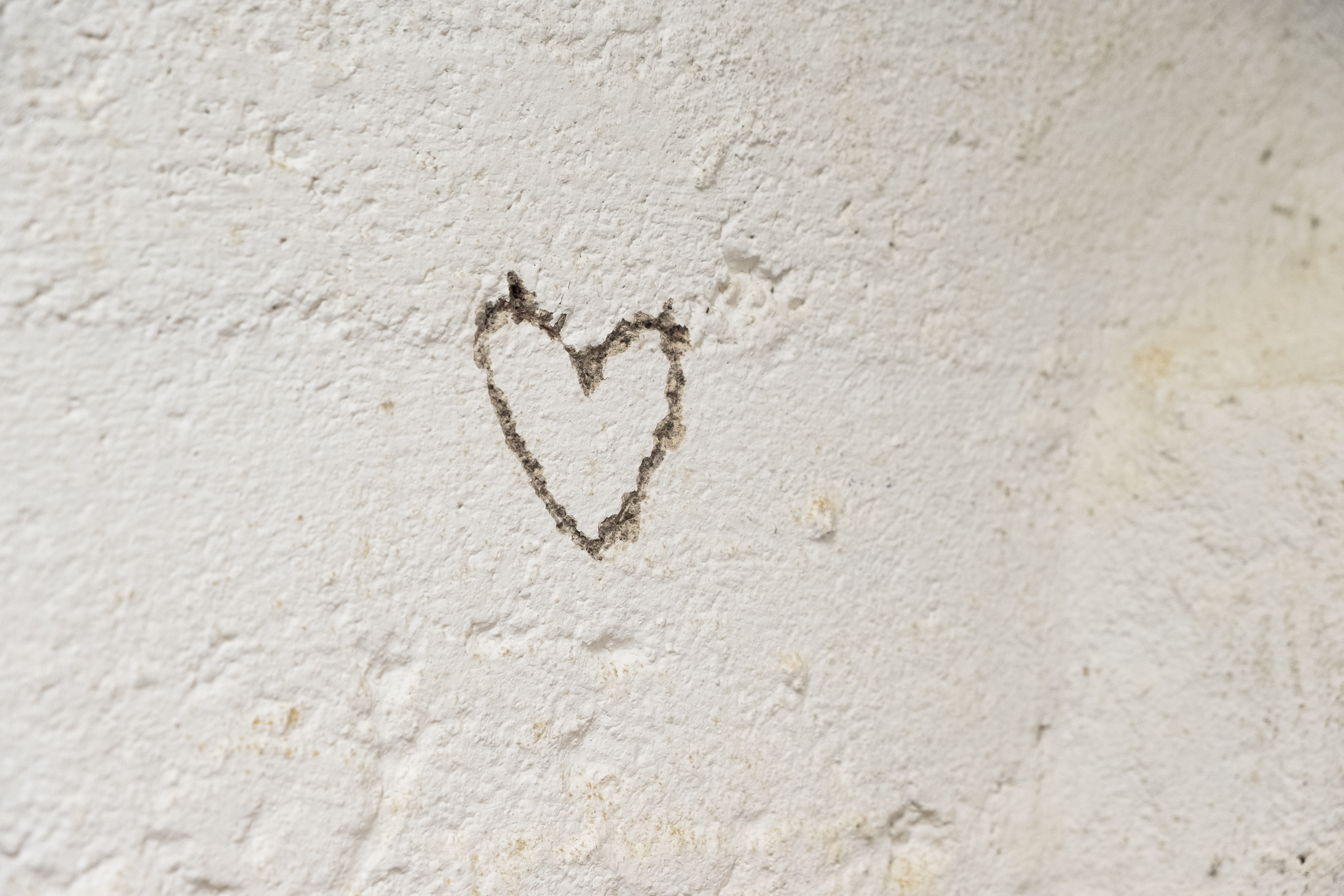 Ett hjärta inristat i en vit stenvägg.