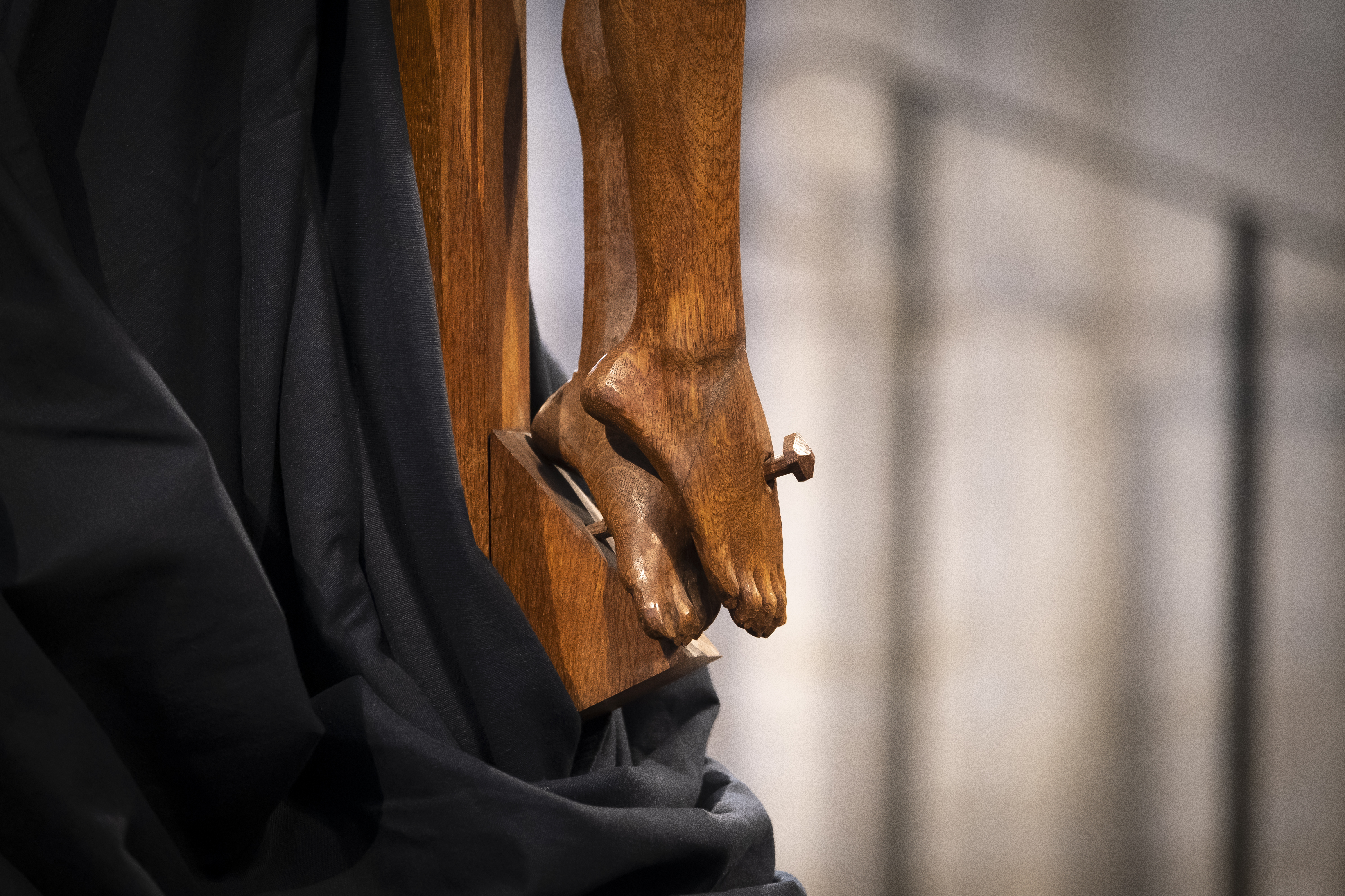 Närbild från ett träkrucifix på Jesus fastspikade fötter.