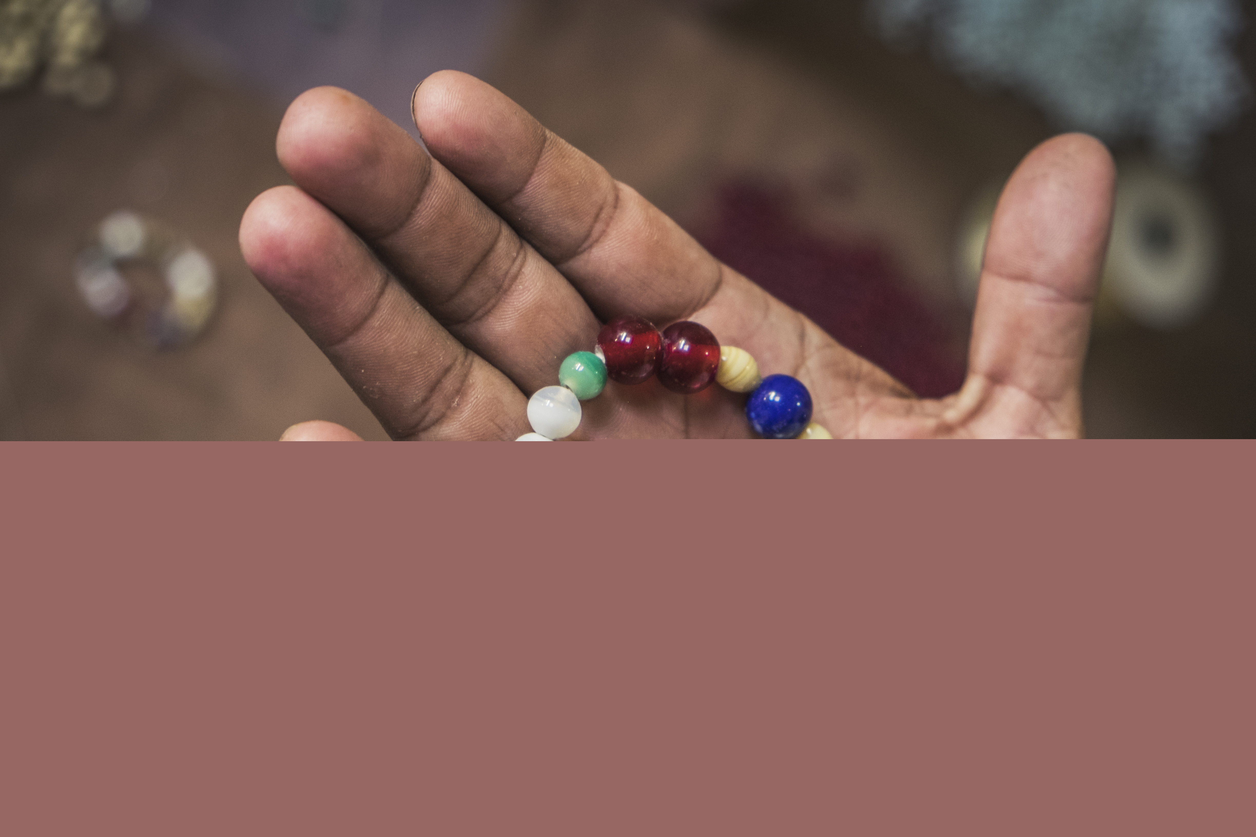 Ett pärlarmband i olika färger ligger i någons hand.