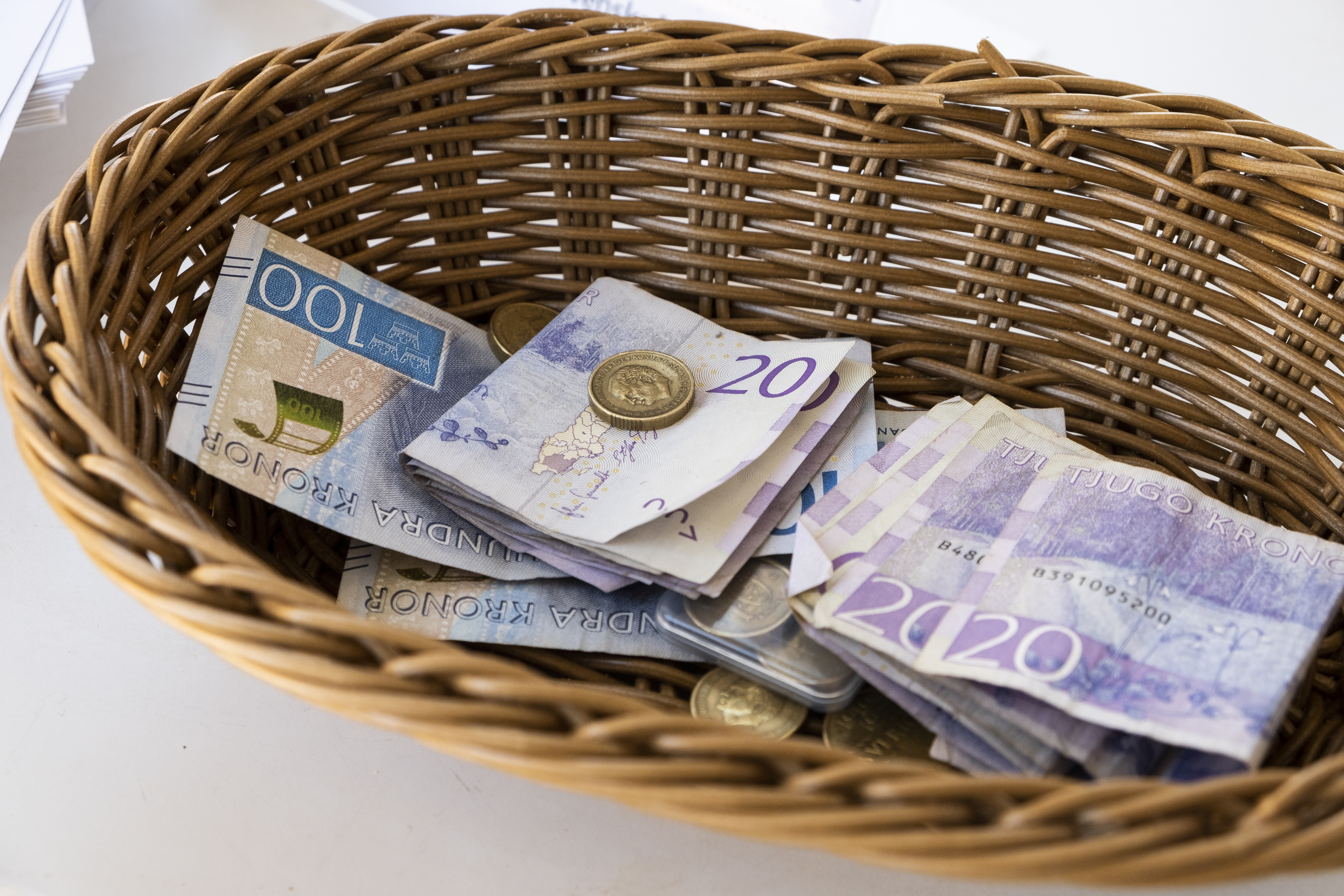 Sedlar och mynt ligger i en kollektkorg.