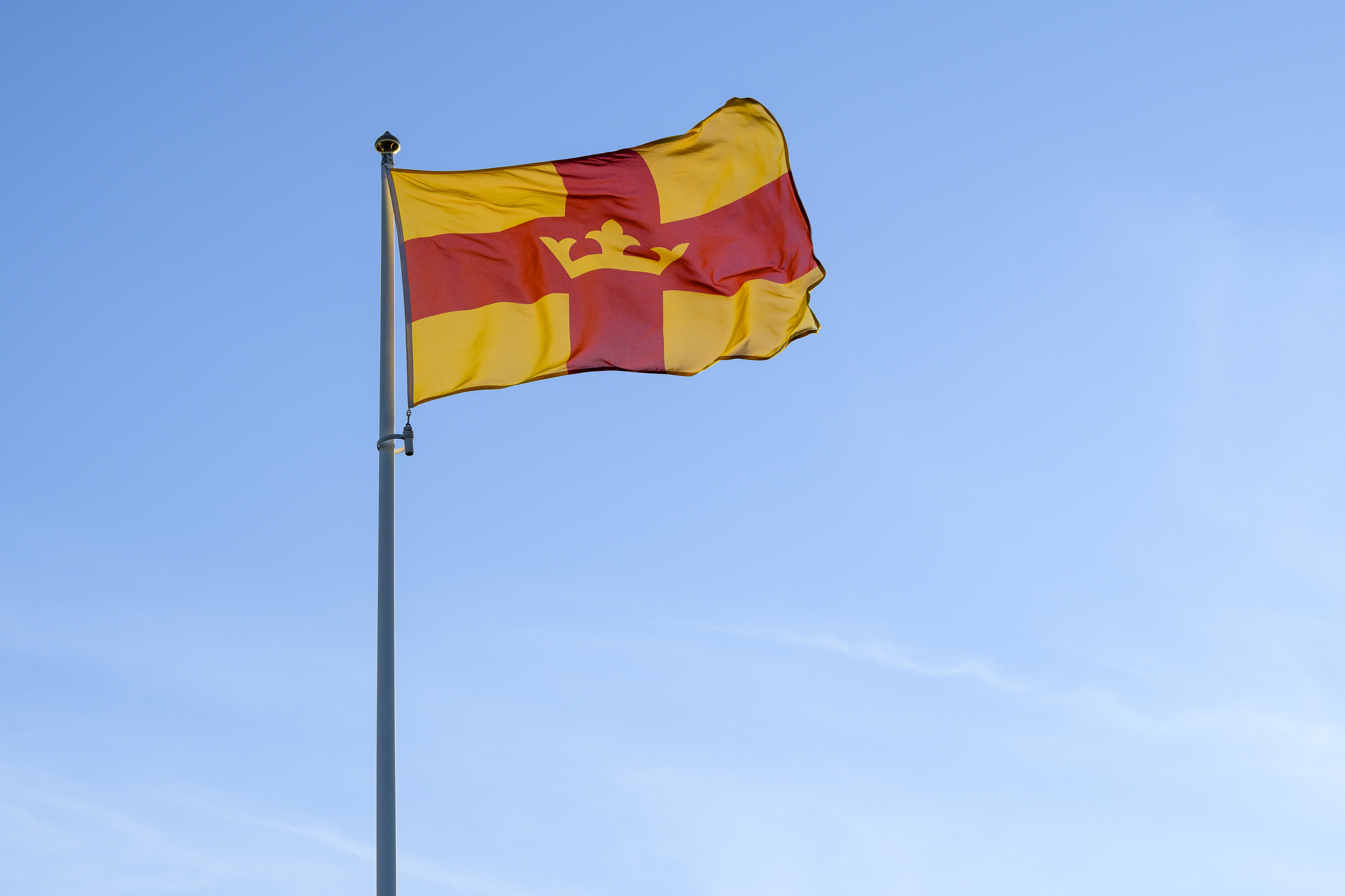 Svenska kyrkans flagga vajar mot en blå himmel.