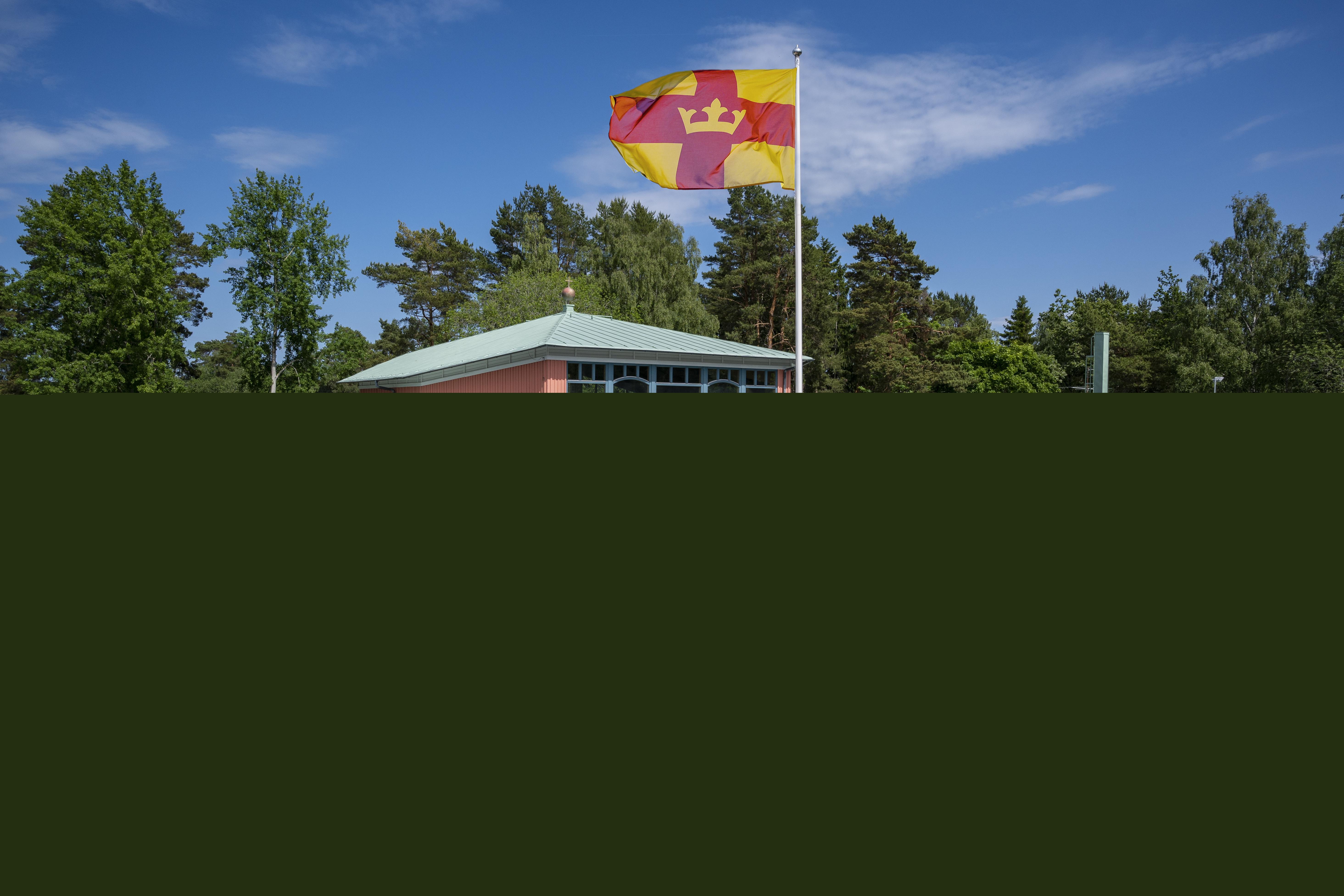 Magdalenakyrkan i Bålsta en solig dag. Svenska kyrkans flagga vajar utanför.