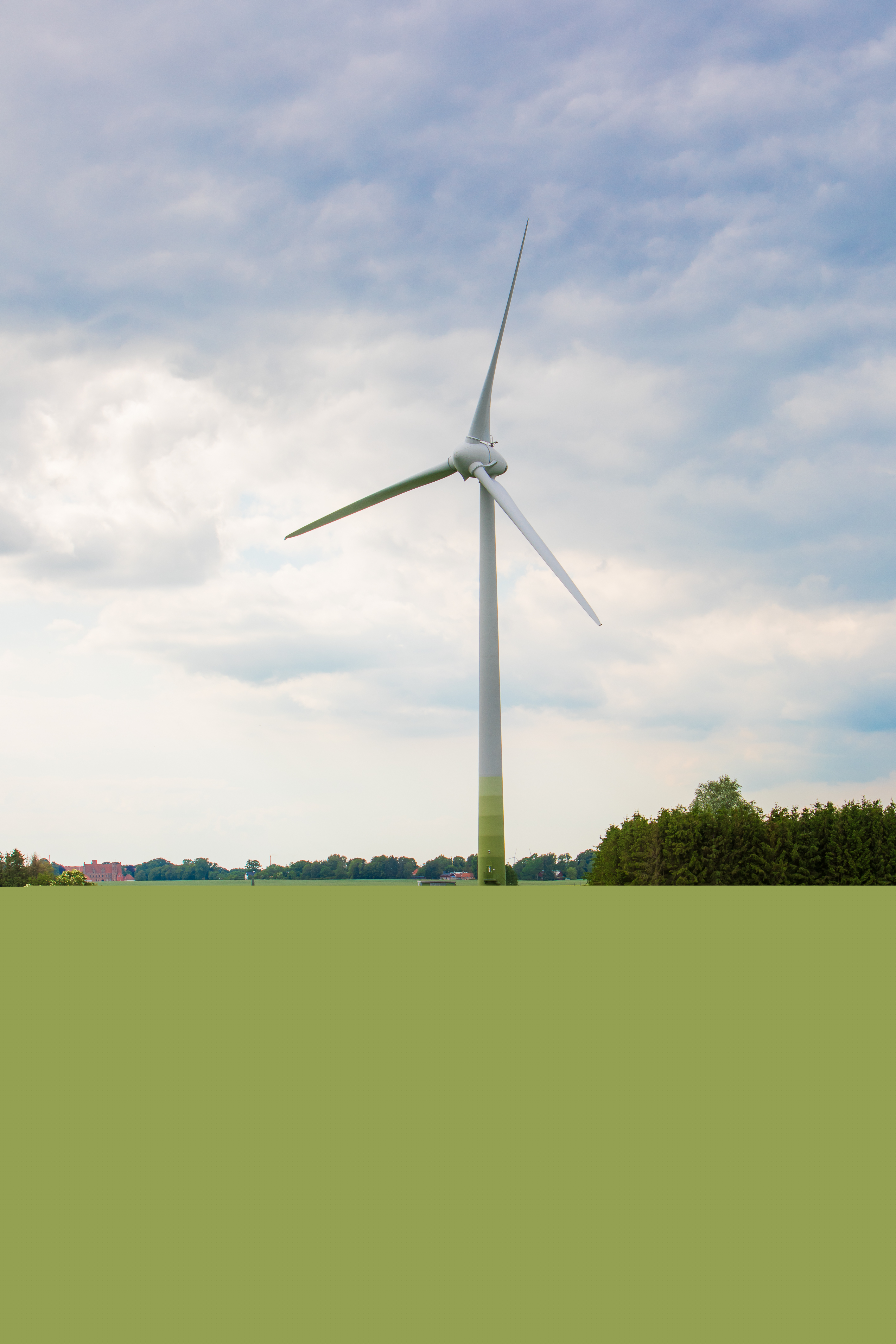 En grusväg leder fram till ett stort vindkraftverk.