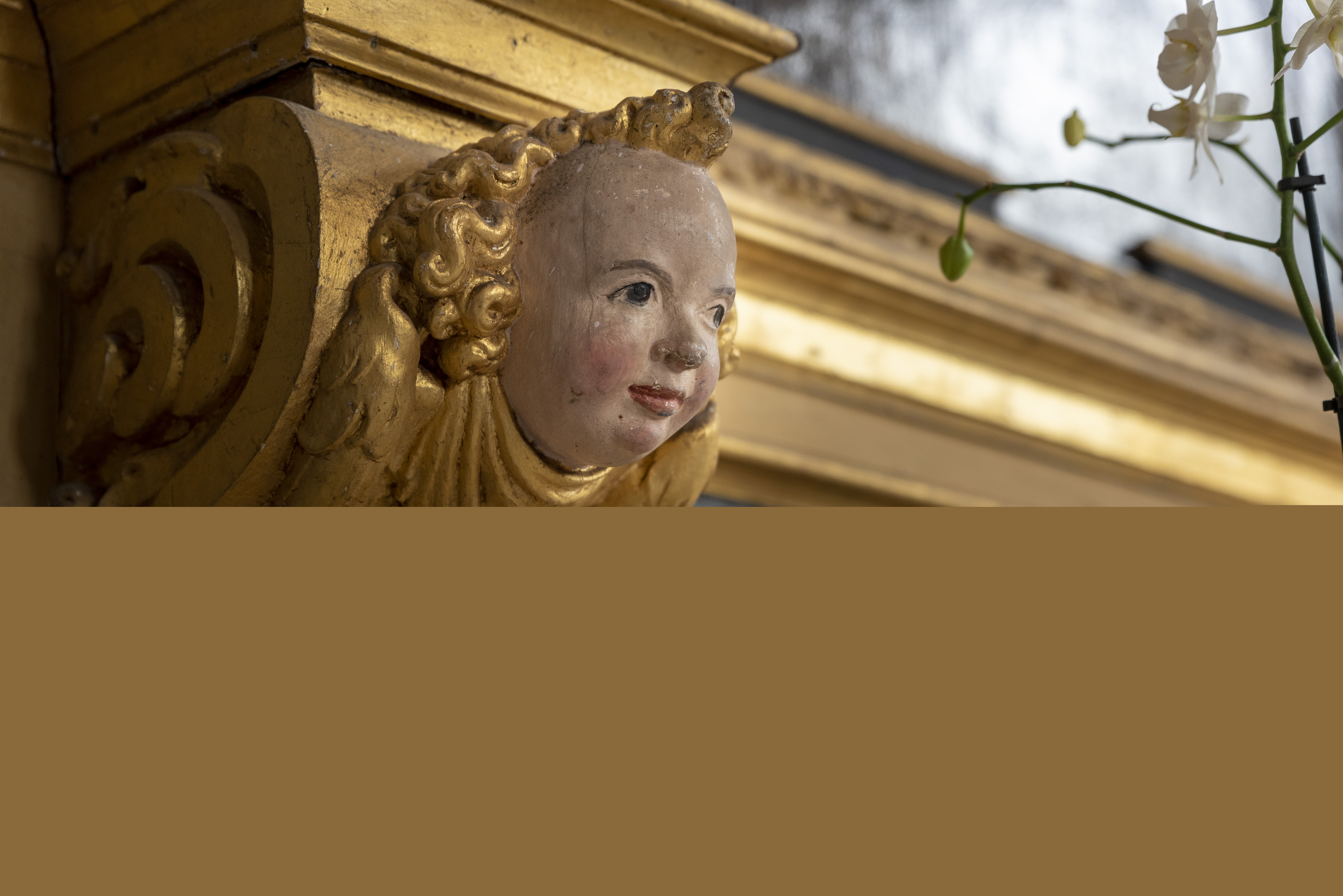 En ängels ansikte i ett guldmålat träornament.