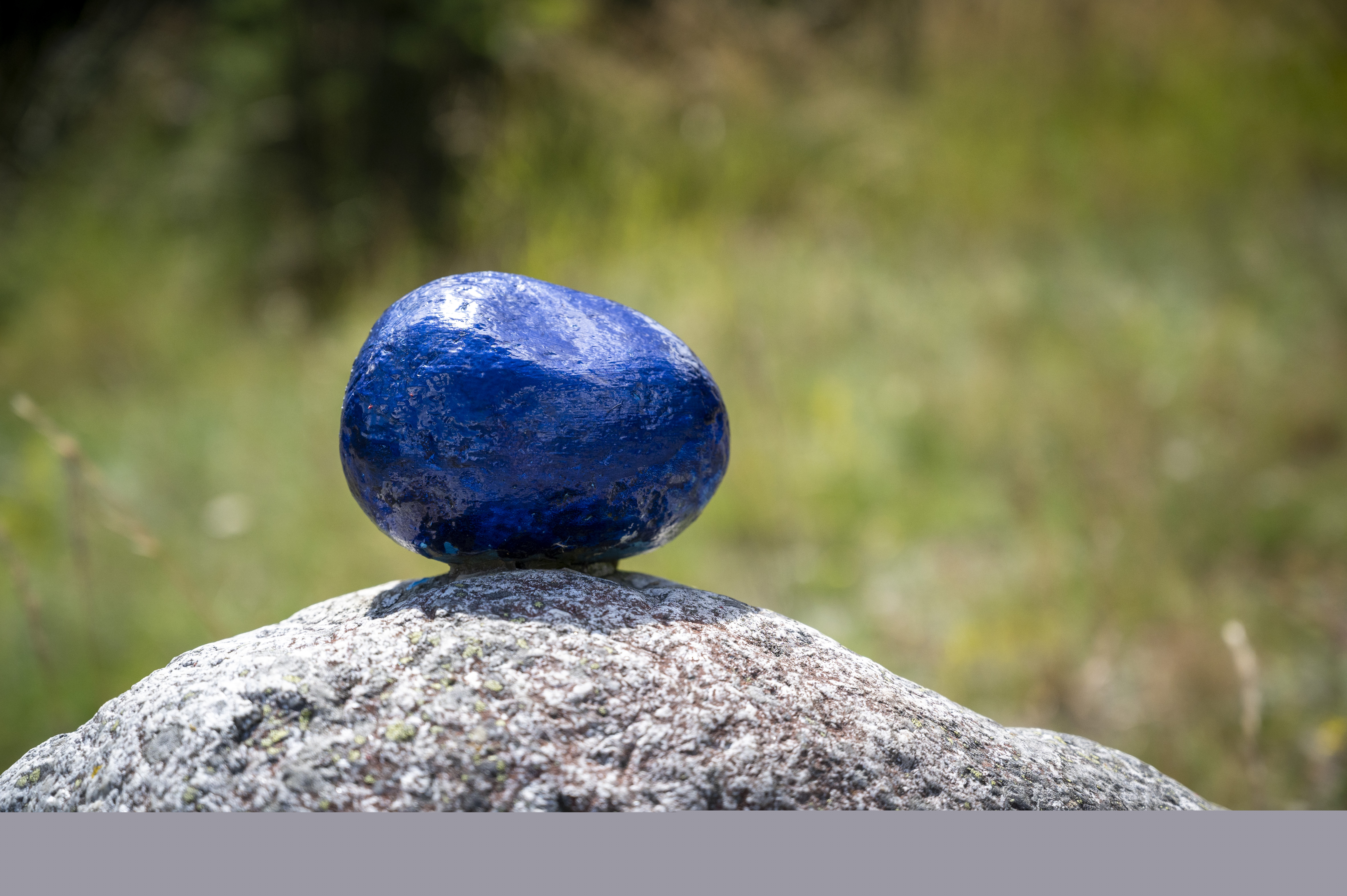 En mindre blåmålad sten ligger ovanpå en större.